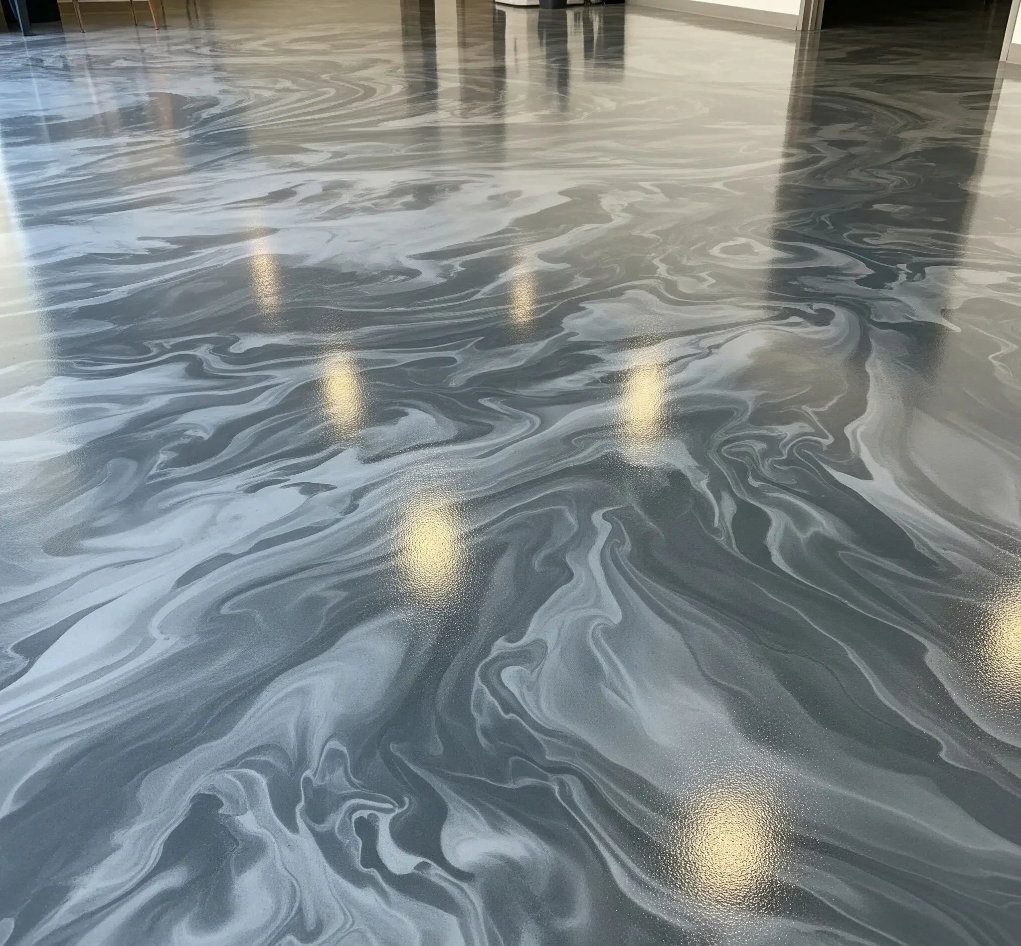 Polished marble floor with swirling gray and white patterns in a modern building lobby.