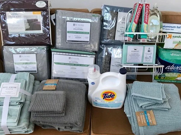 Collection of household items including blankets, towels, Tide laundry detergent, and assorted cleaning supplies.