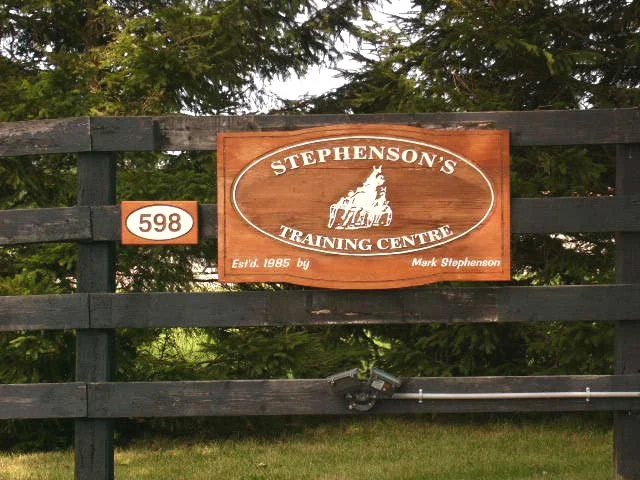 	
Wooden sign for Stephenson's Training Centre attached to a black fence, with trees in the background.