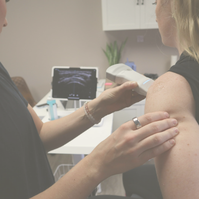 A healthcare professional performing an ultrasound on a patient's shoulder in a medical office.