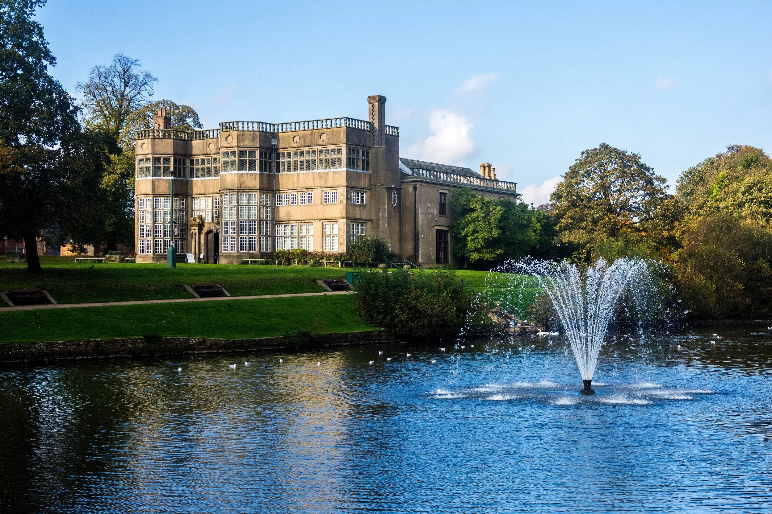 Astley Park Hall and lake fountain in the sunshine.