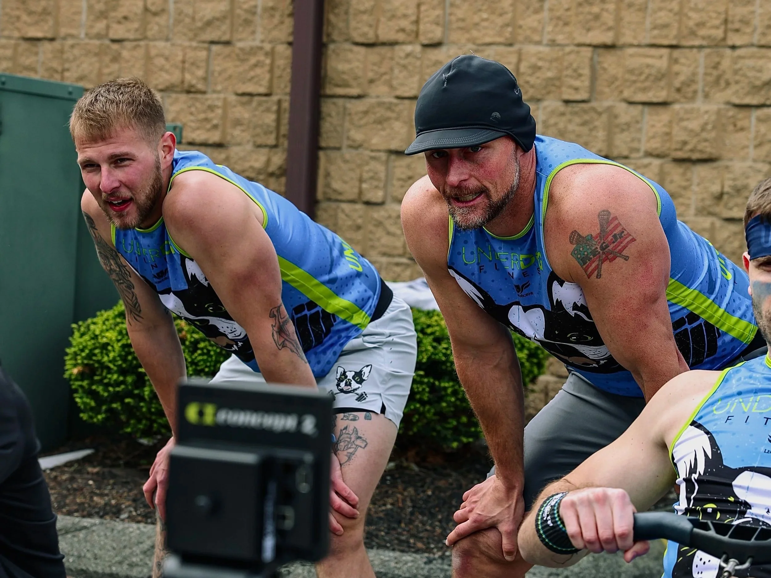 Two men in athletic clothing doing a DEKA MILE event at Underdog Fitness.