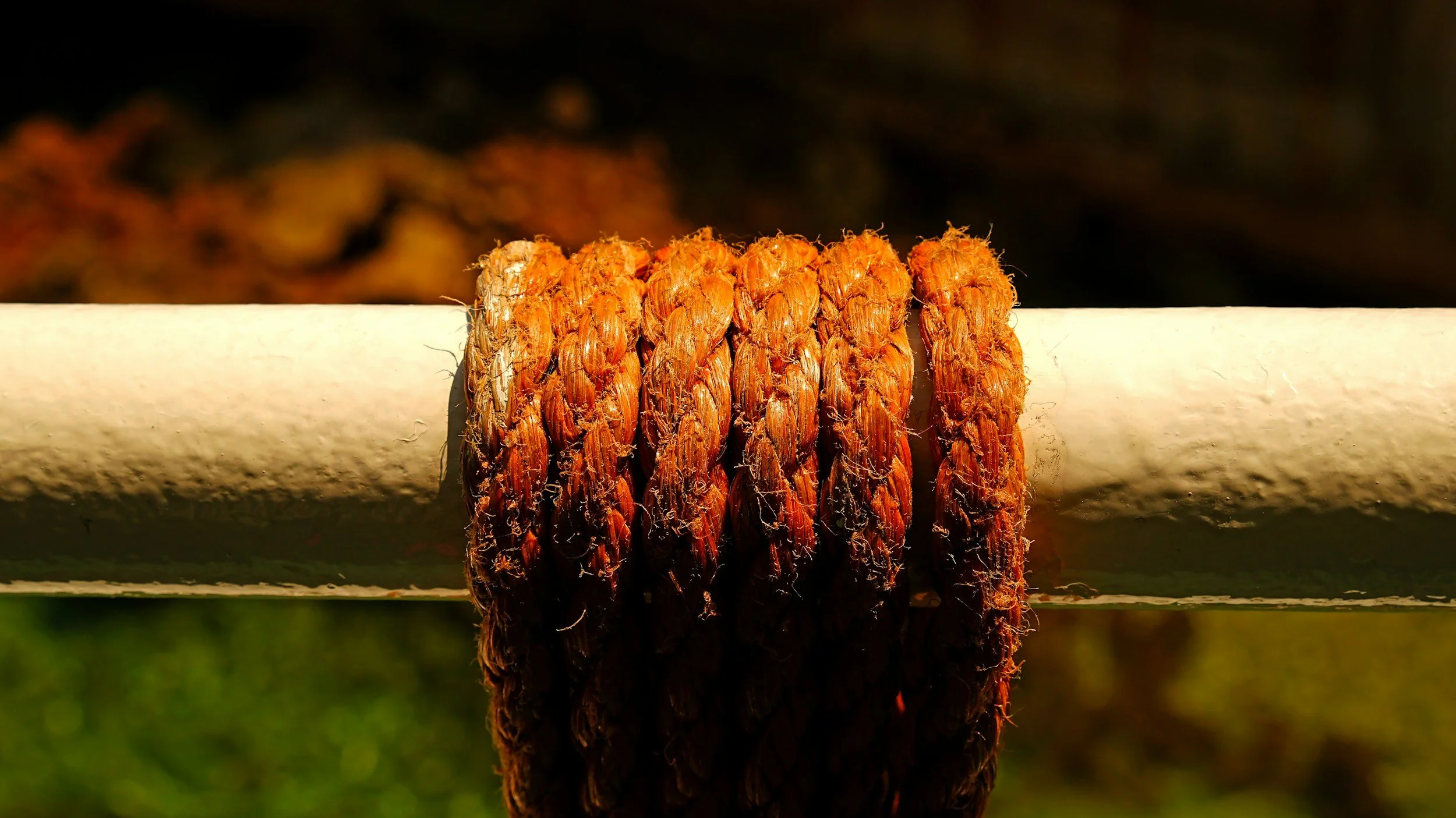 Close-up of a weathered, rusty metal post with orange-brown corrosion, against a blurred background.