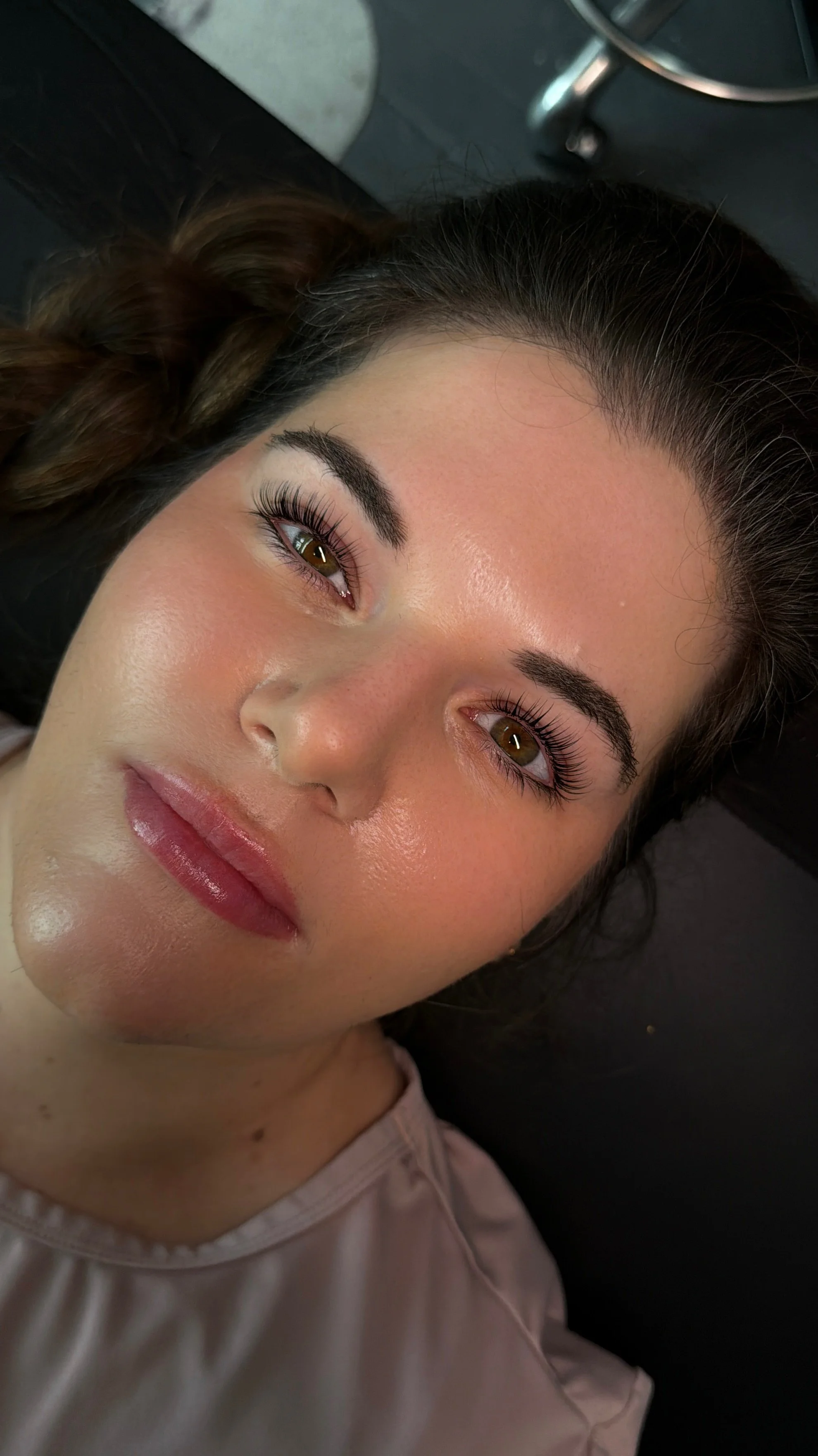 A woman lying down with makeup and eyelash extensions.