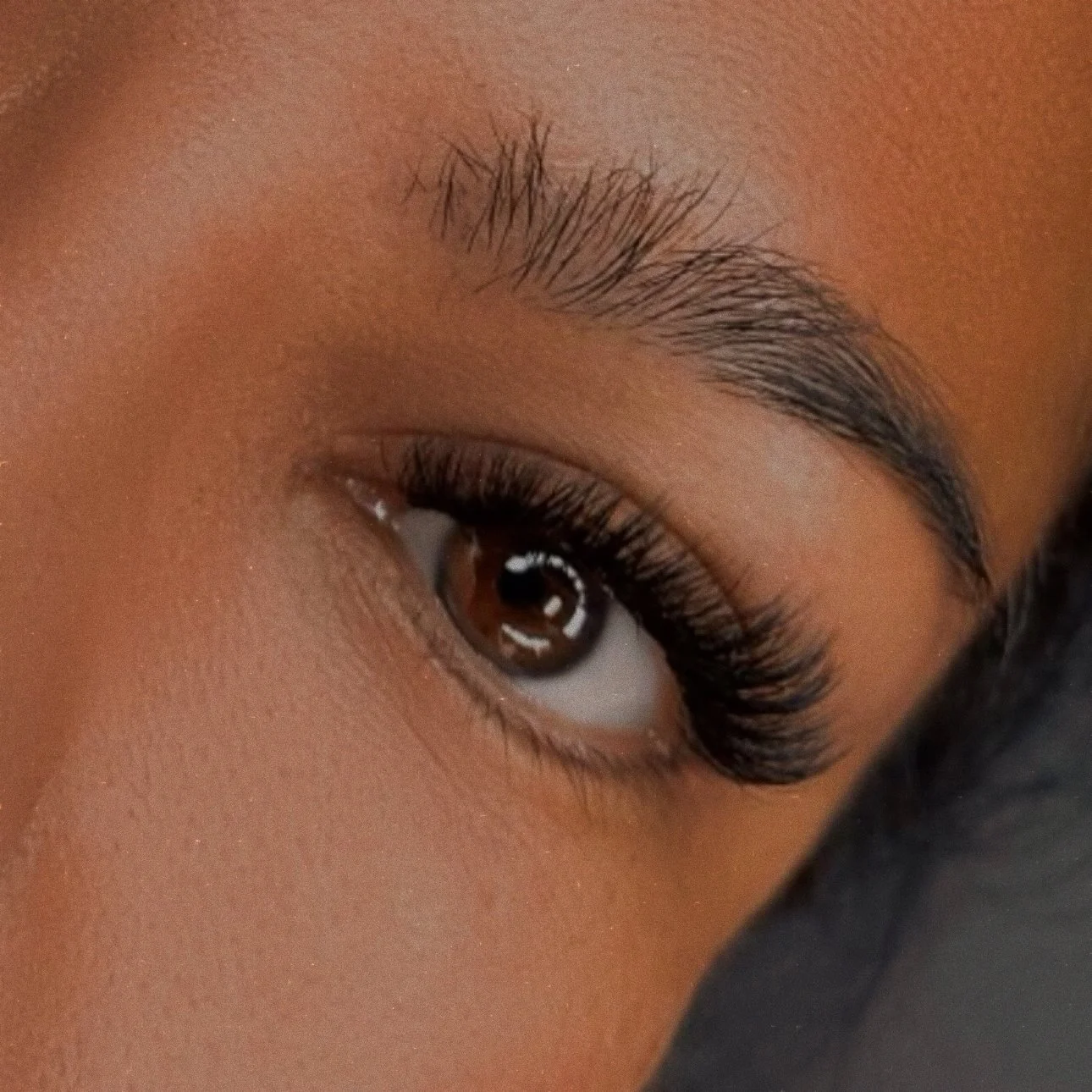 Close-up of a person's eye with long, dark eyelashes and well-groomed eyebrow.