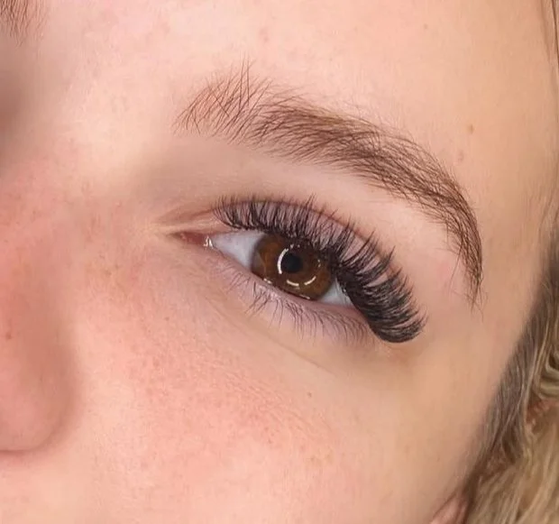 Close-up of a person's eye with long, curled eyelashes and well-groomed eyebrow.