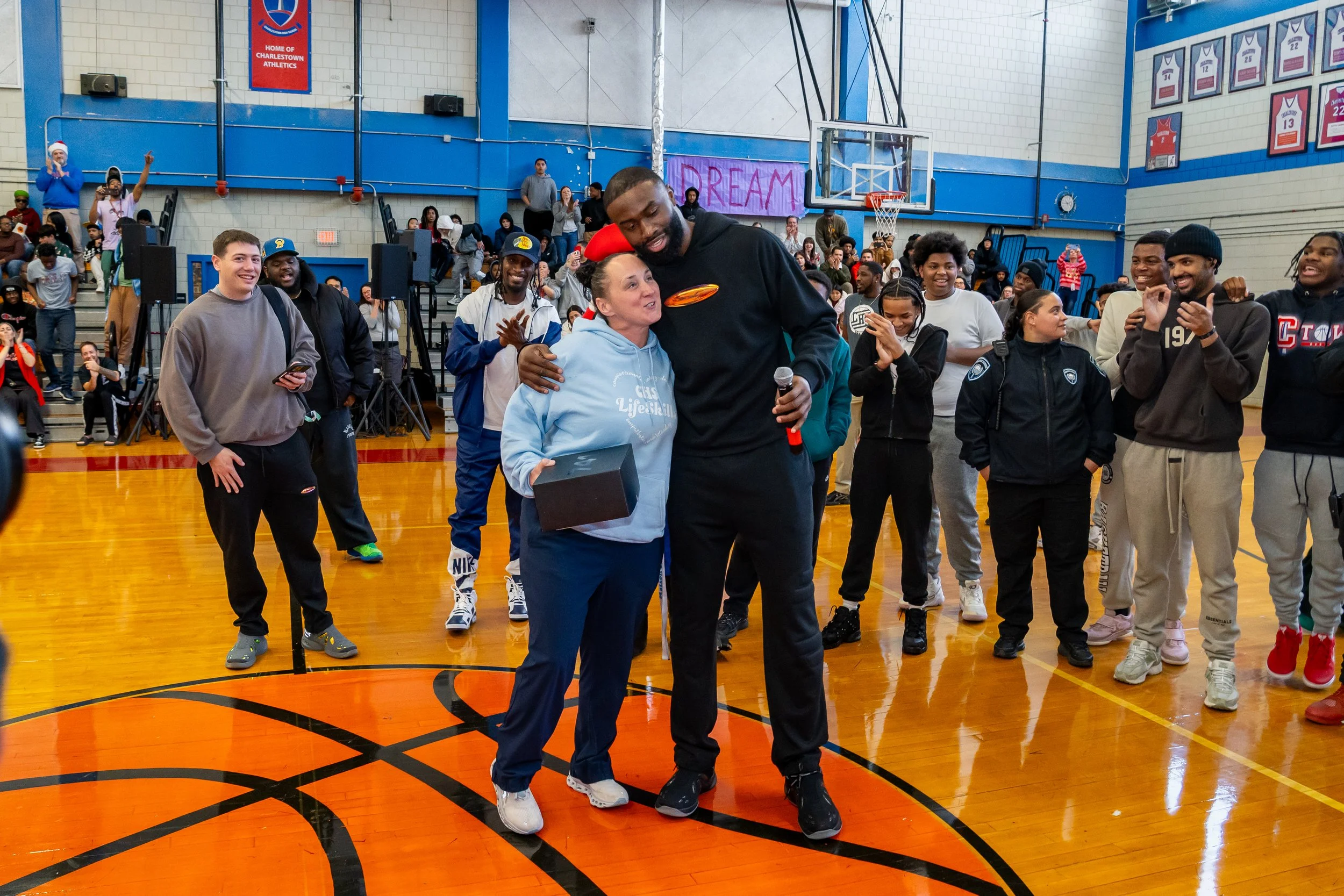 NBA Star and former Boston Celtics and current Philadelphia 76ers basketball player Jaylen Brown embraces a Charlestown High School staff member.