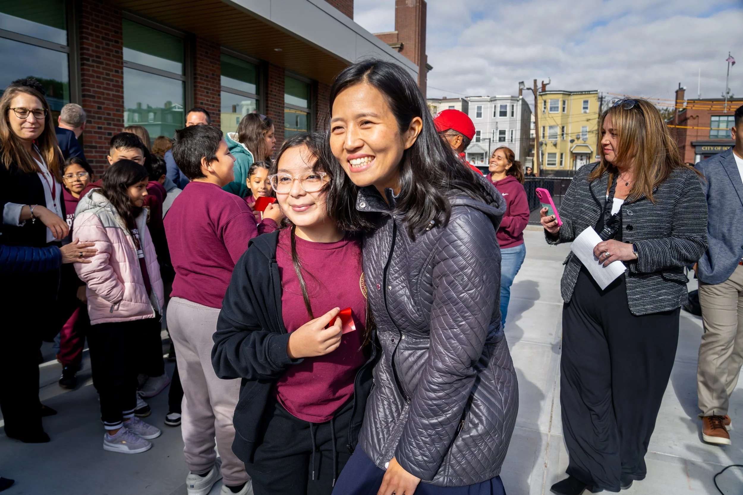 City of Boston Mayor Michelle Wu smiles and poses for a photo with a student. 