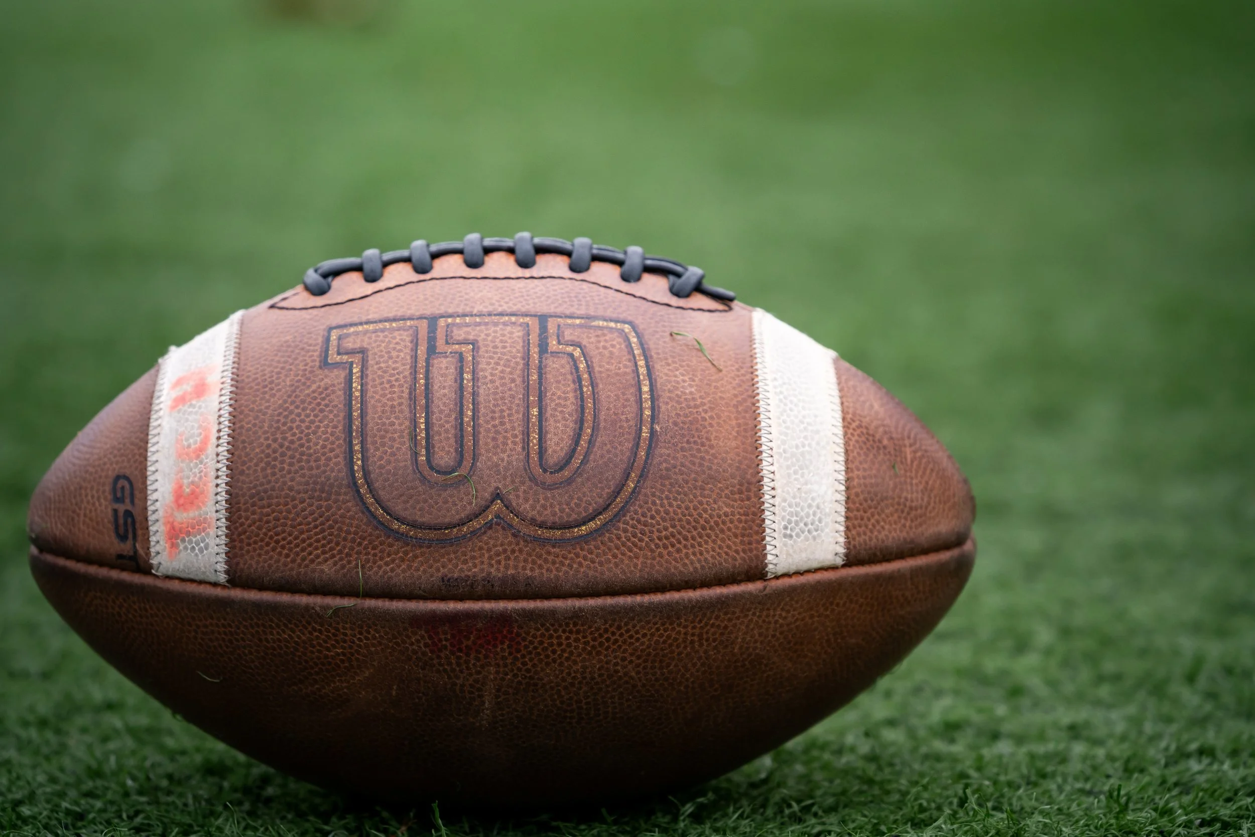 A worn leather football with "Tech" written on it.