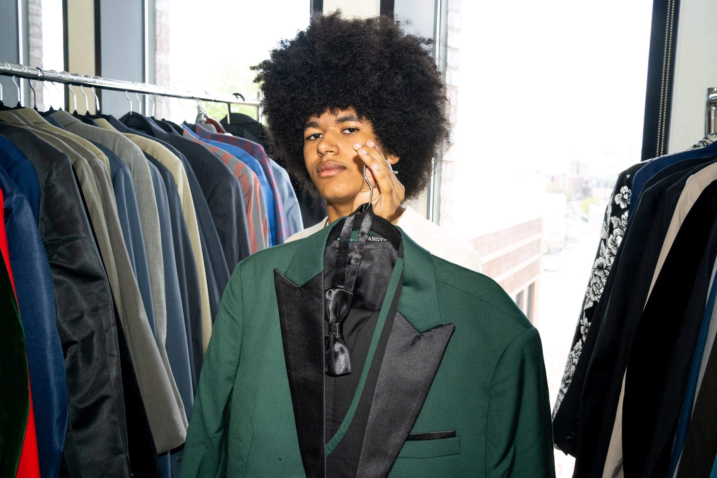 Boston Public Schools student poses for a photo with a green suit jacket. 