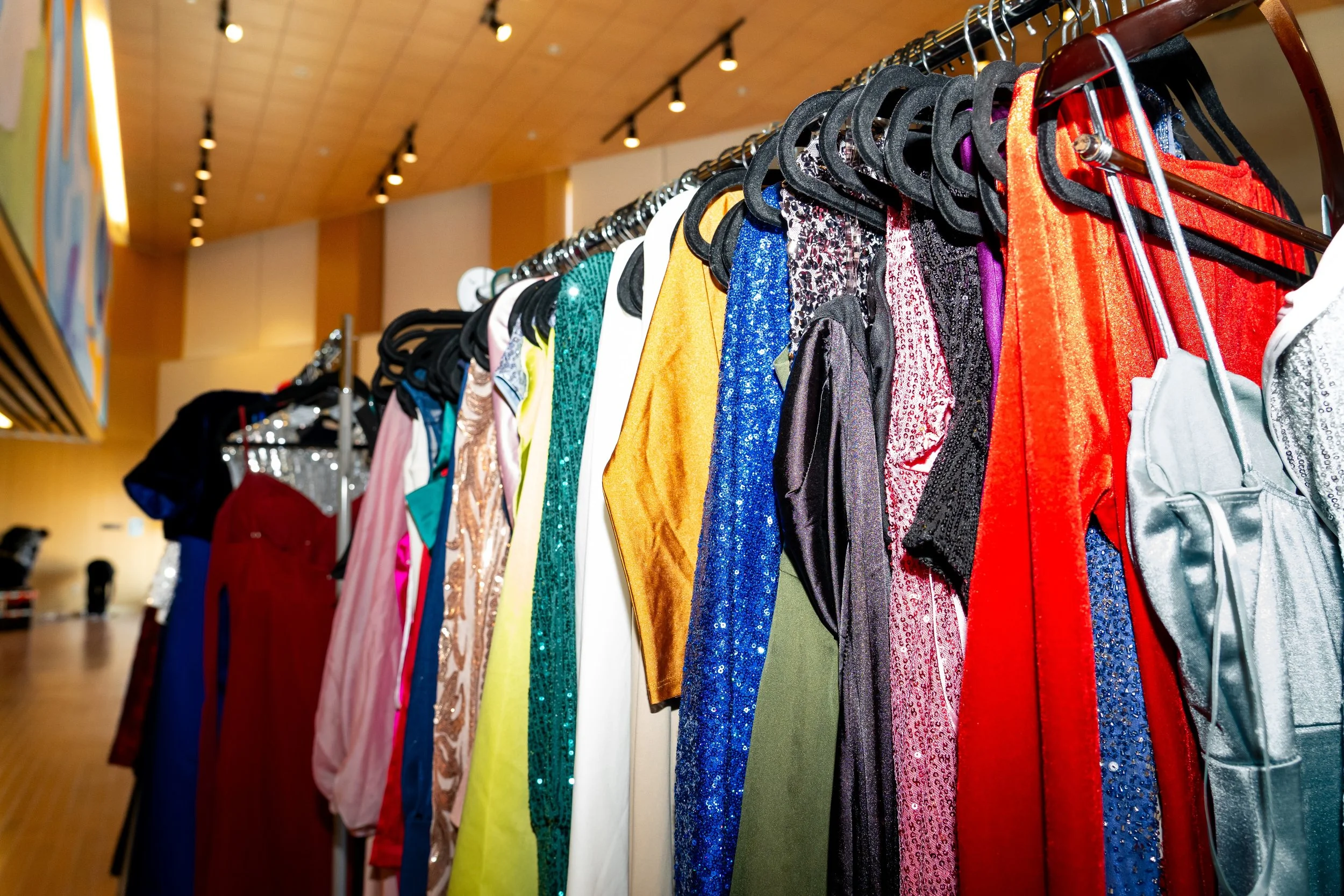 A rack of bright-colored formal dresses.