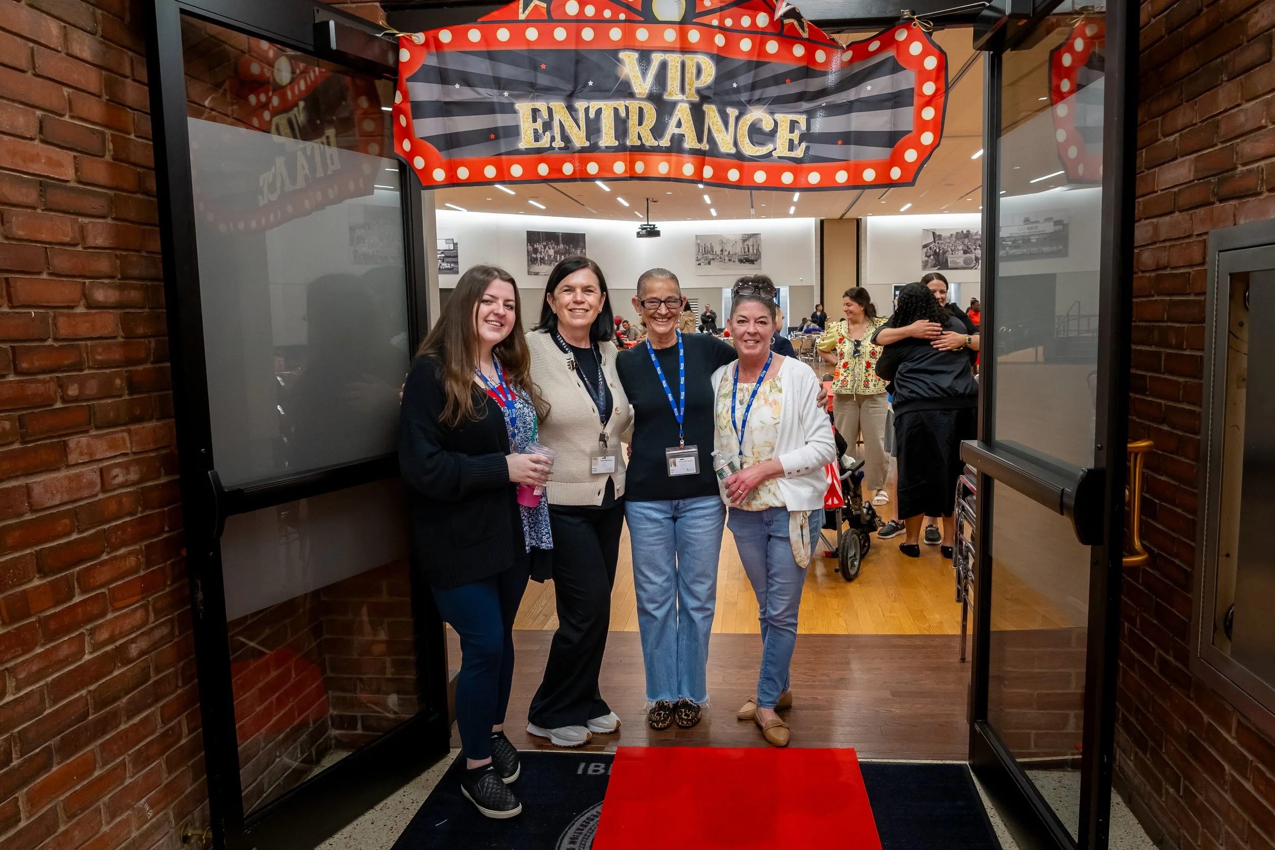 A group of Boston Public Schools educators pose for a photo with a sign above them that reads "VIP Entrance."