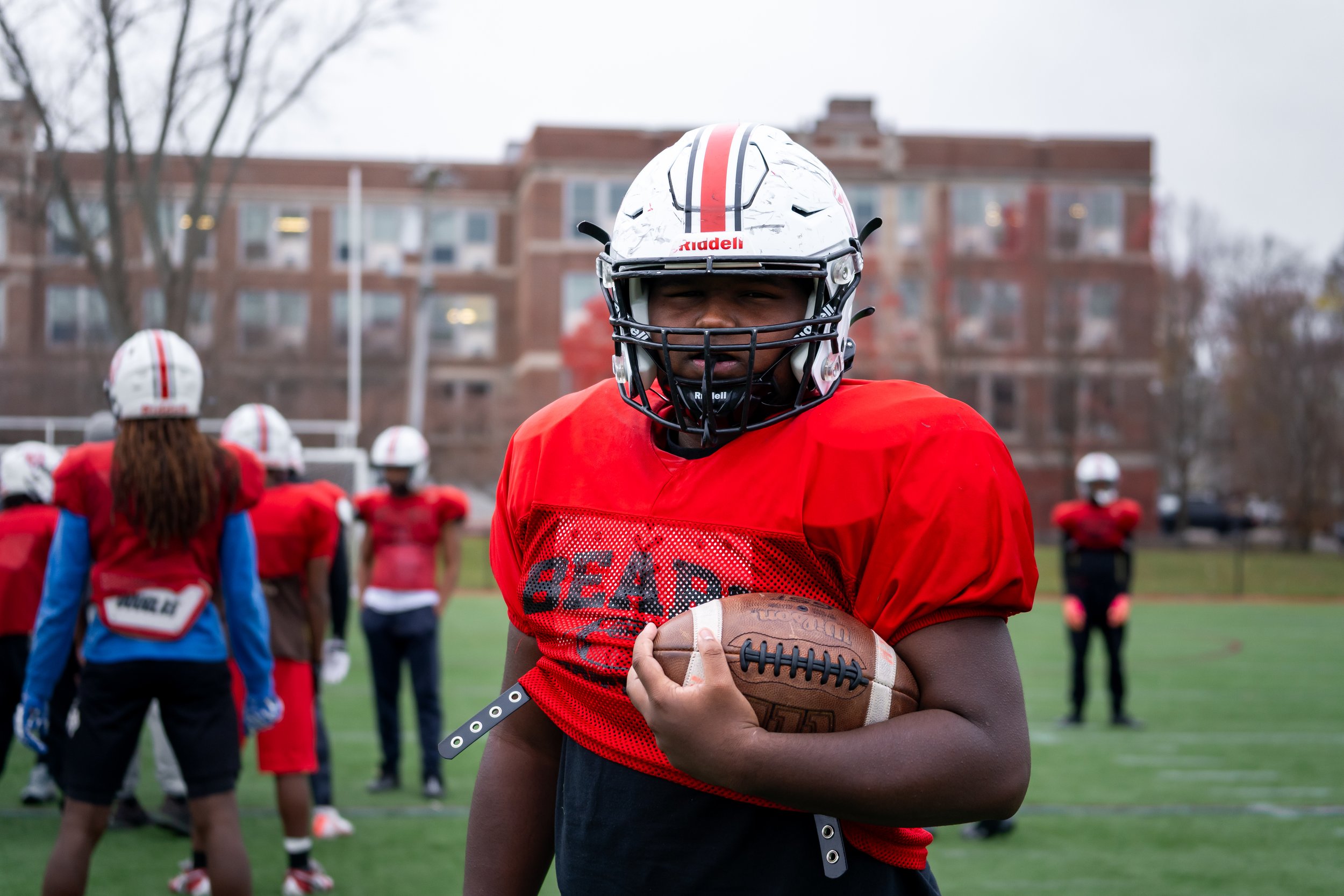 Boston Public Schools football player Edgar Santana Castro poses with a football in his arm. 
