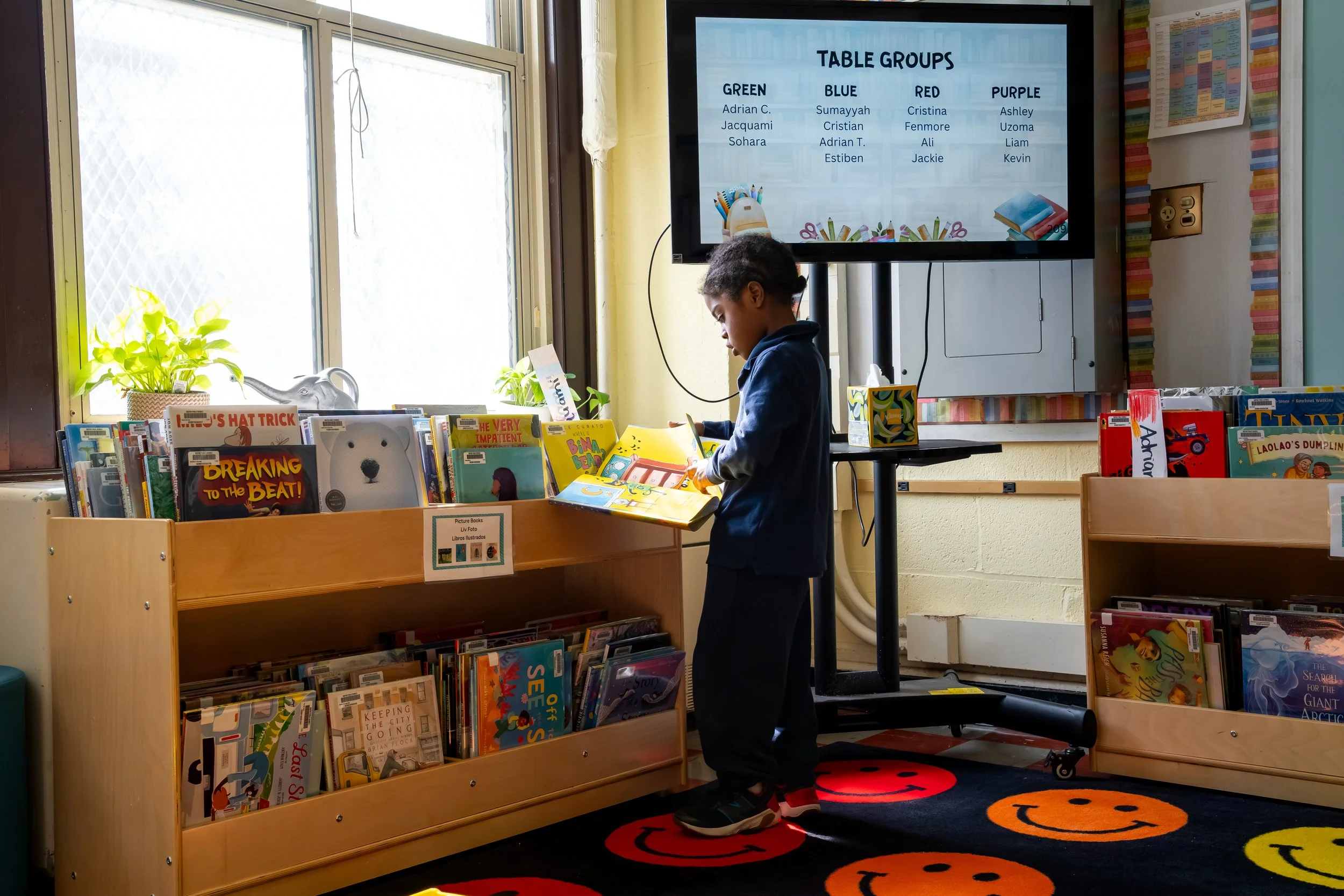 Boston Public Schools student reads and flips through a book at the Chittick Elementary School library.