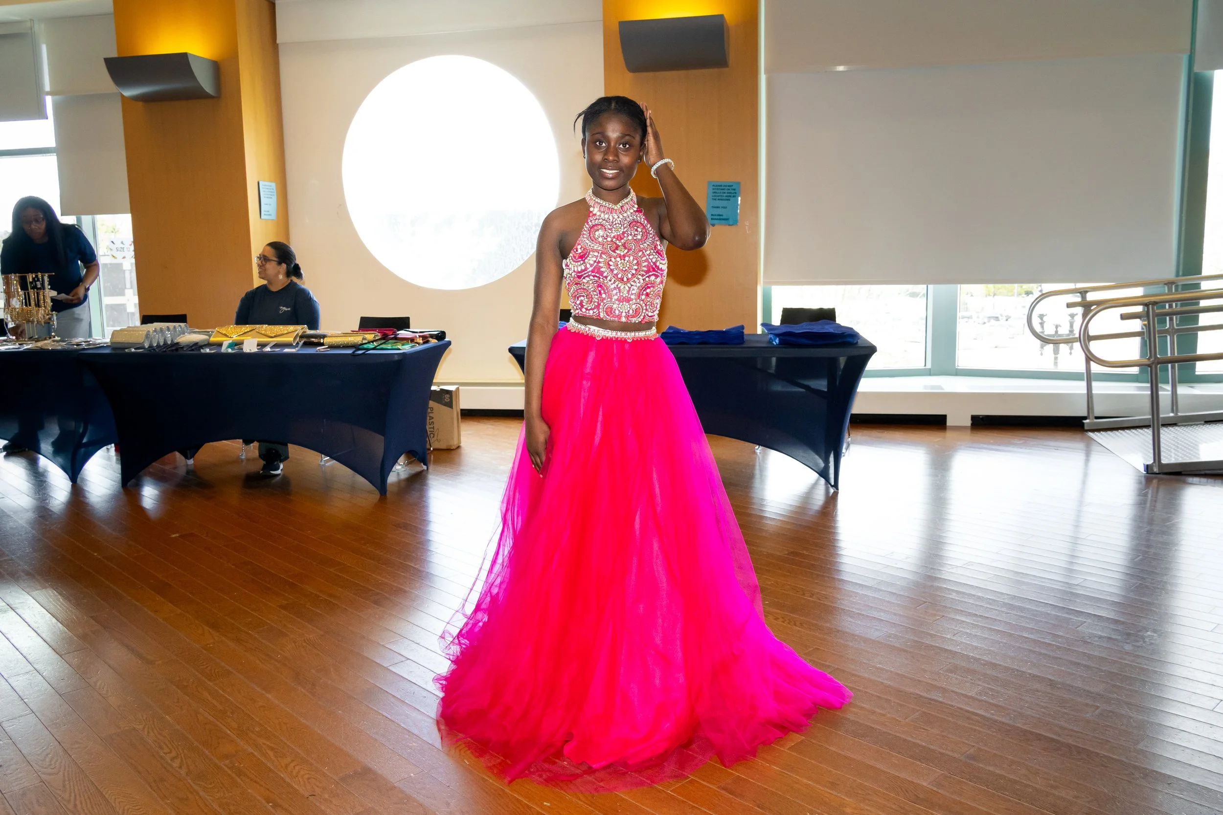 Boston Public Schools student posess for a photo with a bright pink formal dress. 