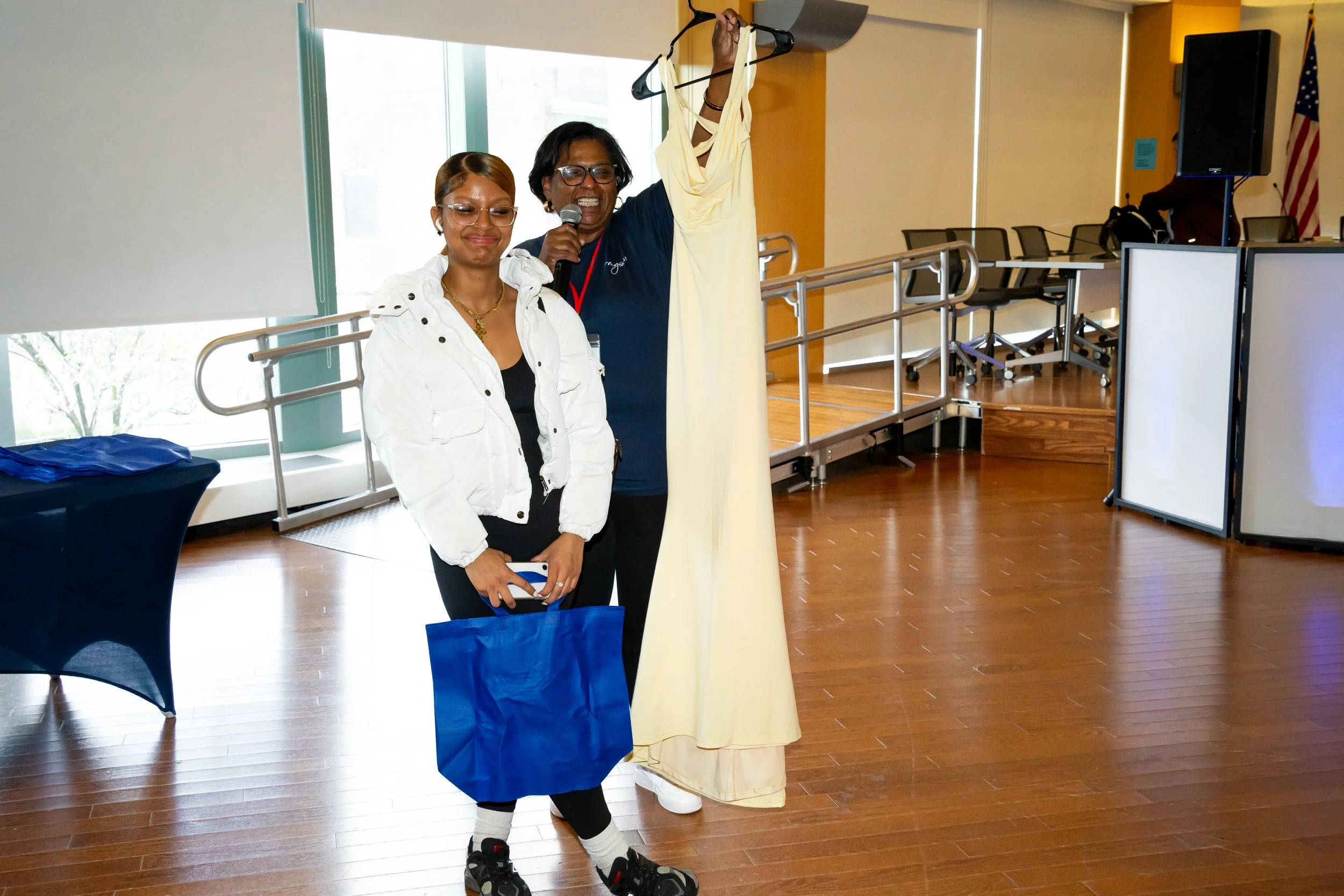 Boston Public Schools staff members holds up a formal dress alongside a student.