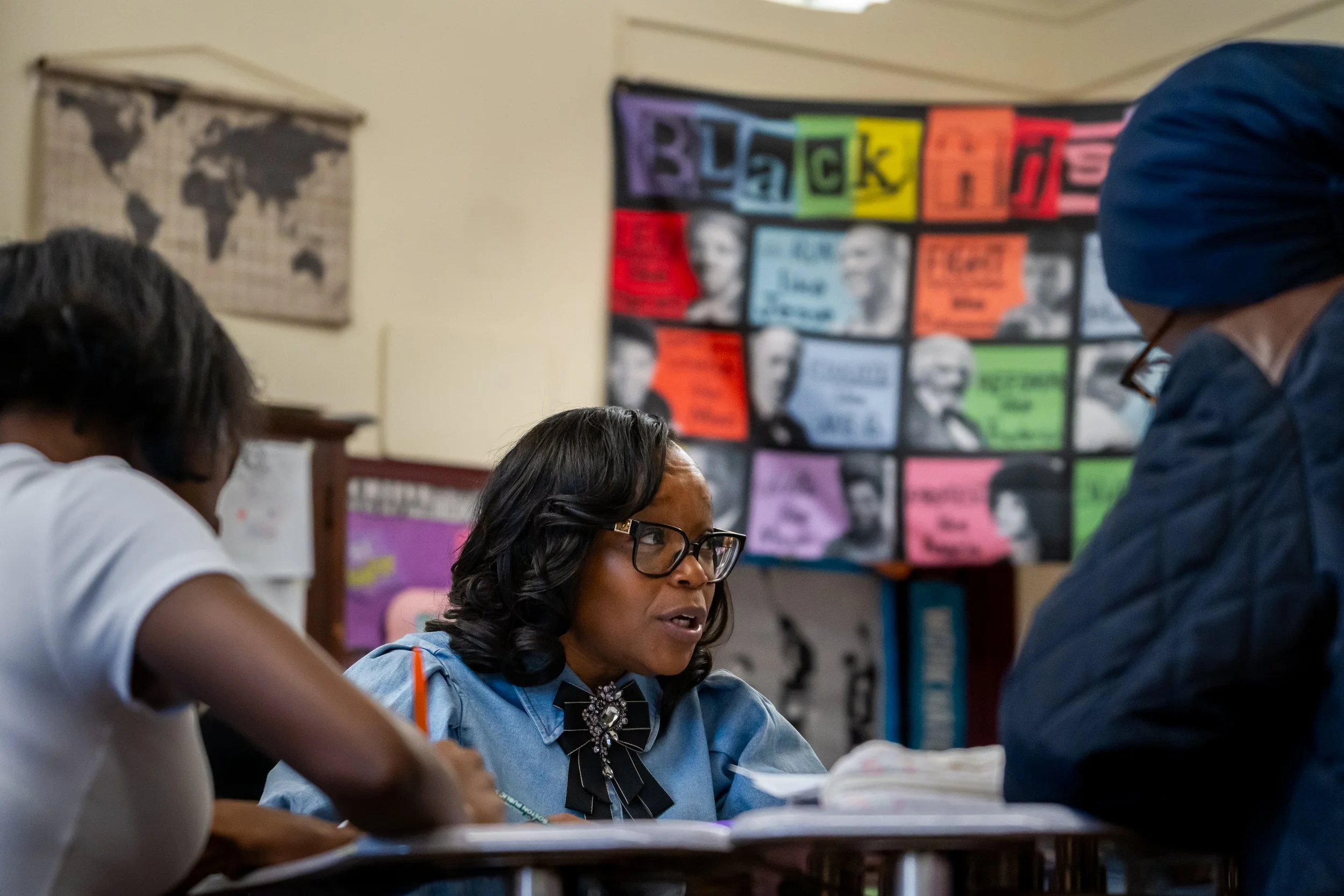 Boston Public Schools educator Tanisha Milton sits at a table and speaks to a group of students.