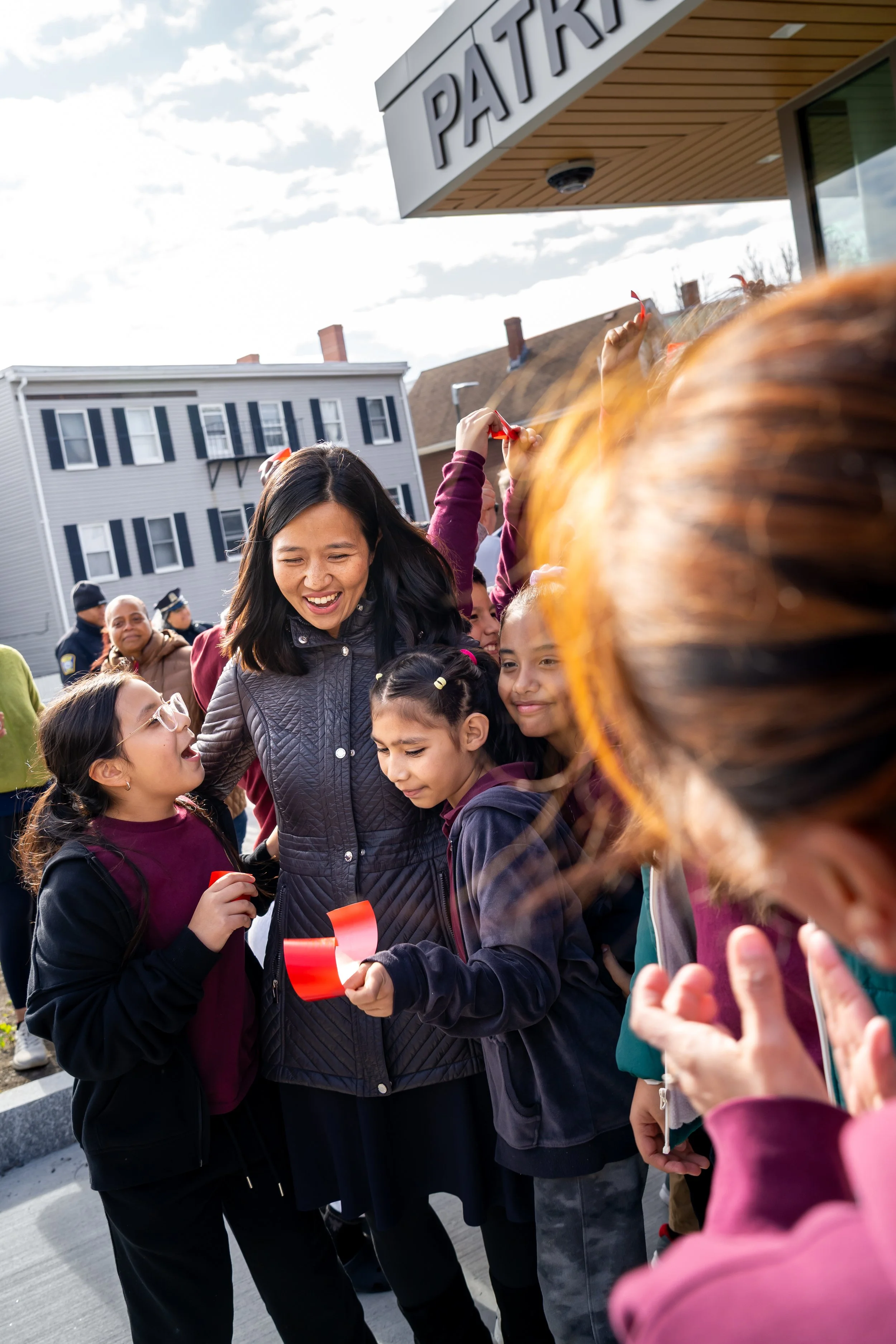 City of Boston Mayor Michelle Wu smiles and embraces Kennedy Elementary students.