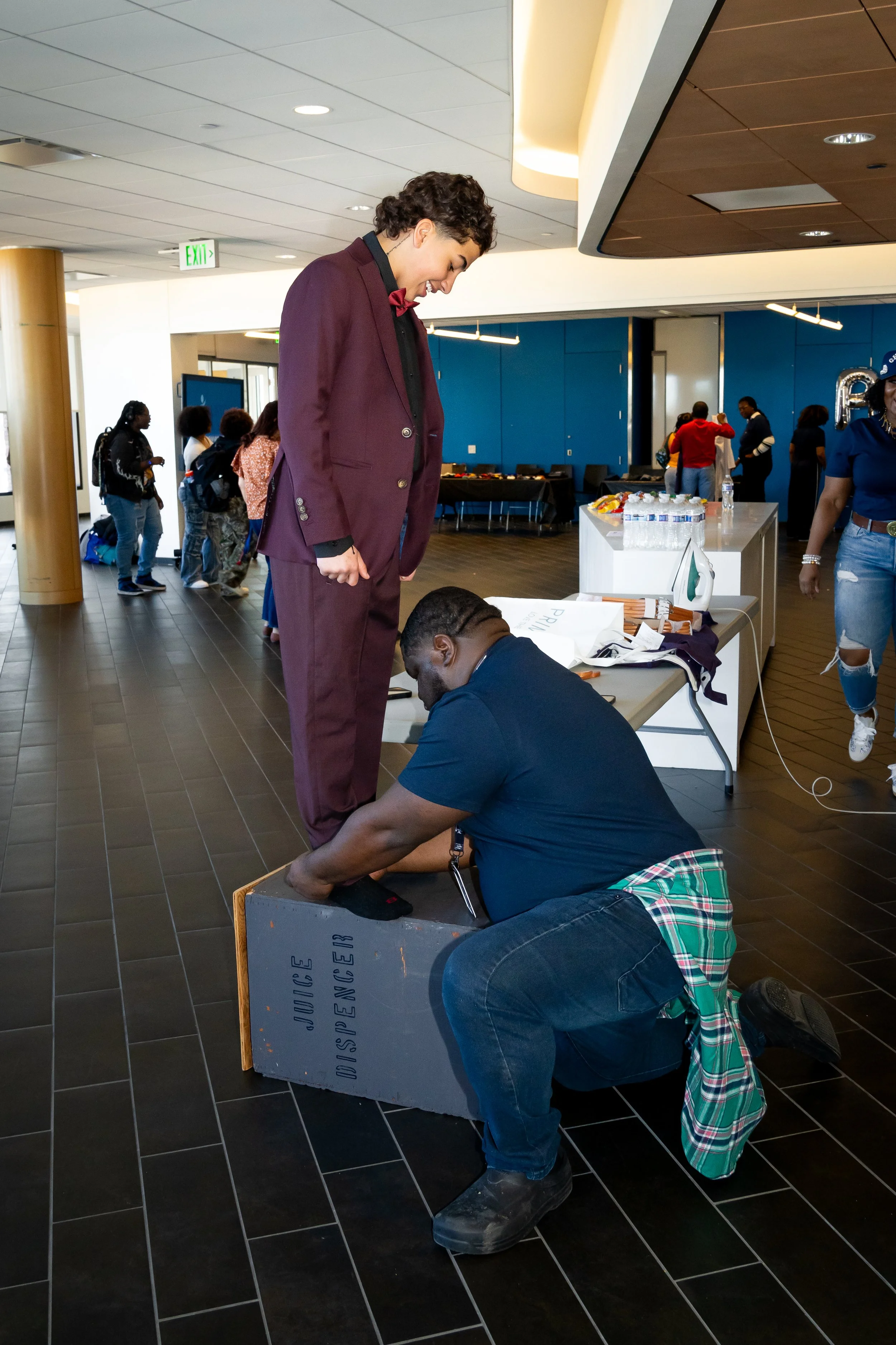 Boston Public Schools staff members assists a student with suit pants.