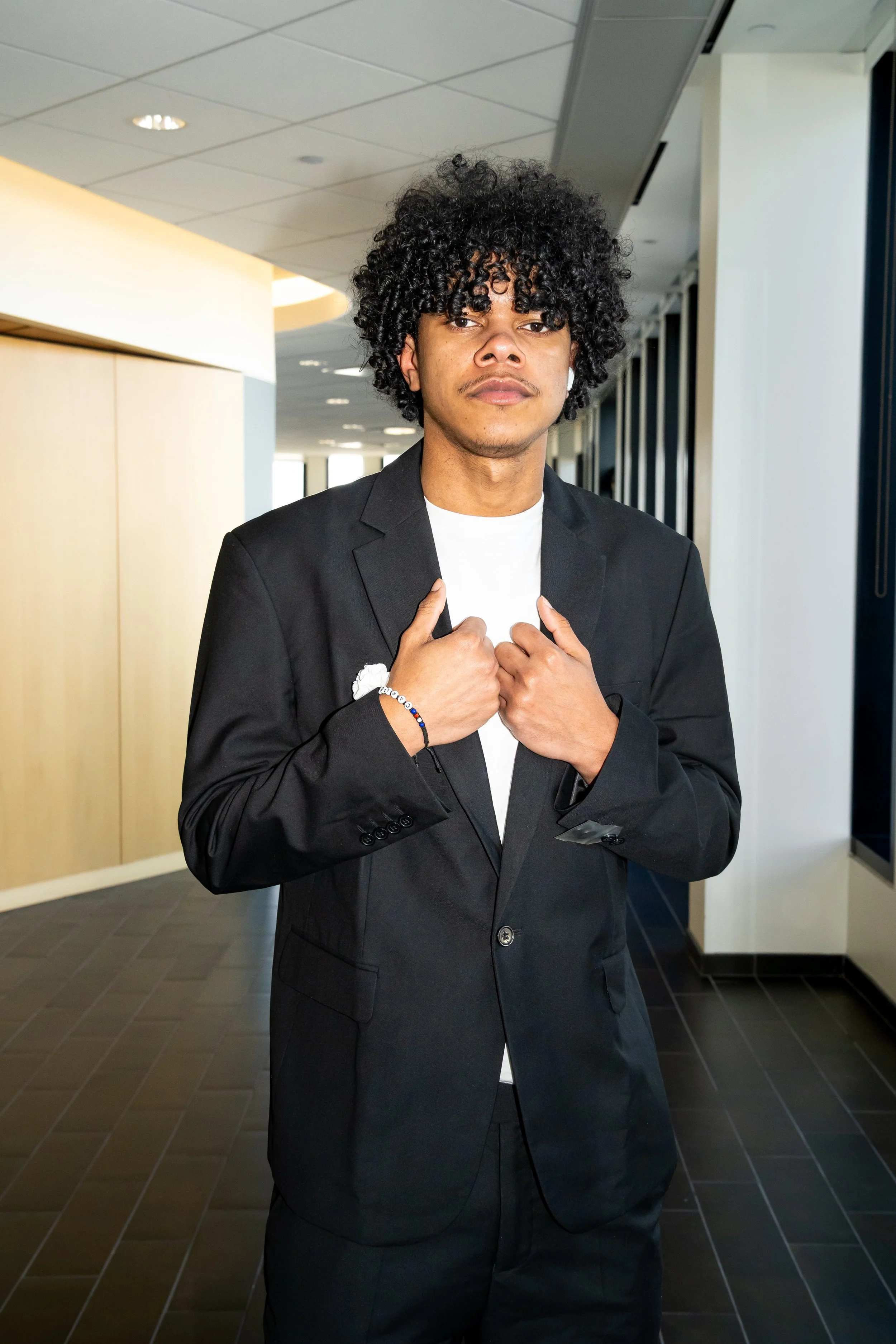 Boston Public Schools student poses for a photo with a black suit jacket. 