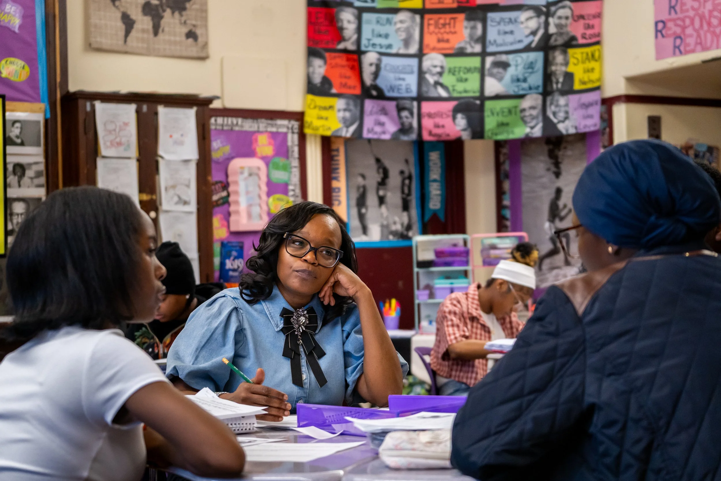 Boston Public Schools educator Tanisha Milton sits at a table and listens to students discuss a lesson.