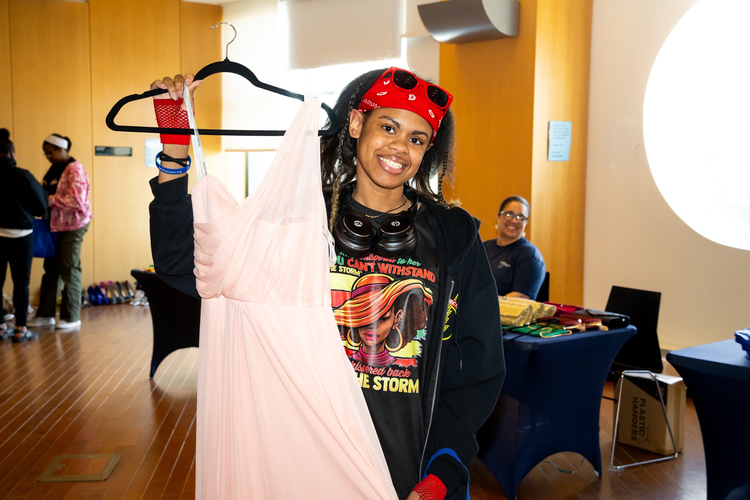 Boston Public Schools student poses for a photo holding a pink formal dress.