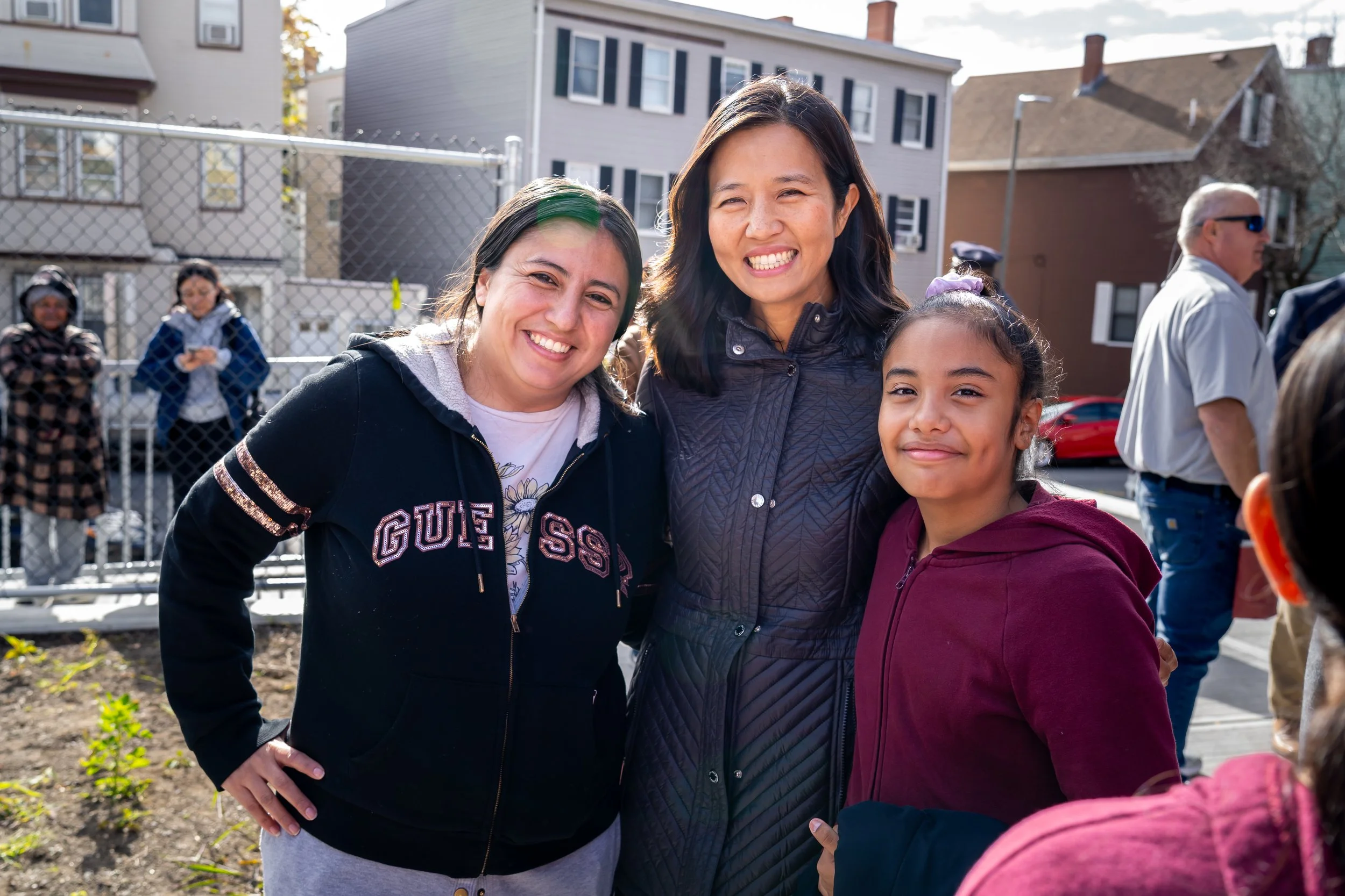City of Boston Mayor Michelle Wu smiles and poses for a photo with Kennedy Elementary student and family member.