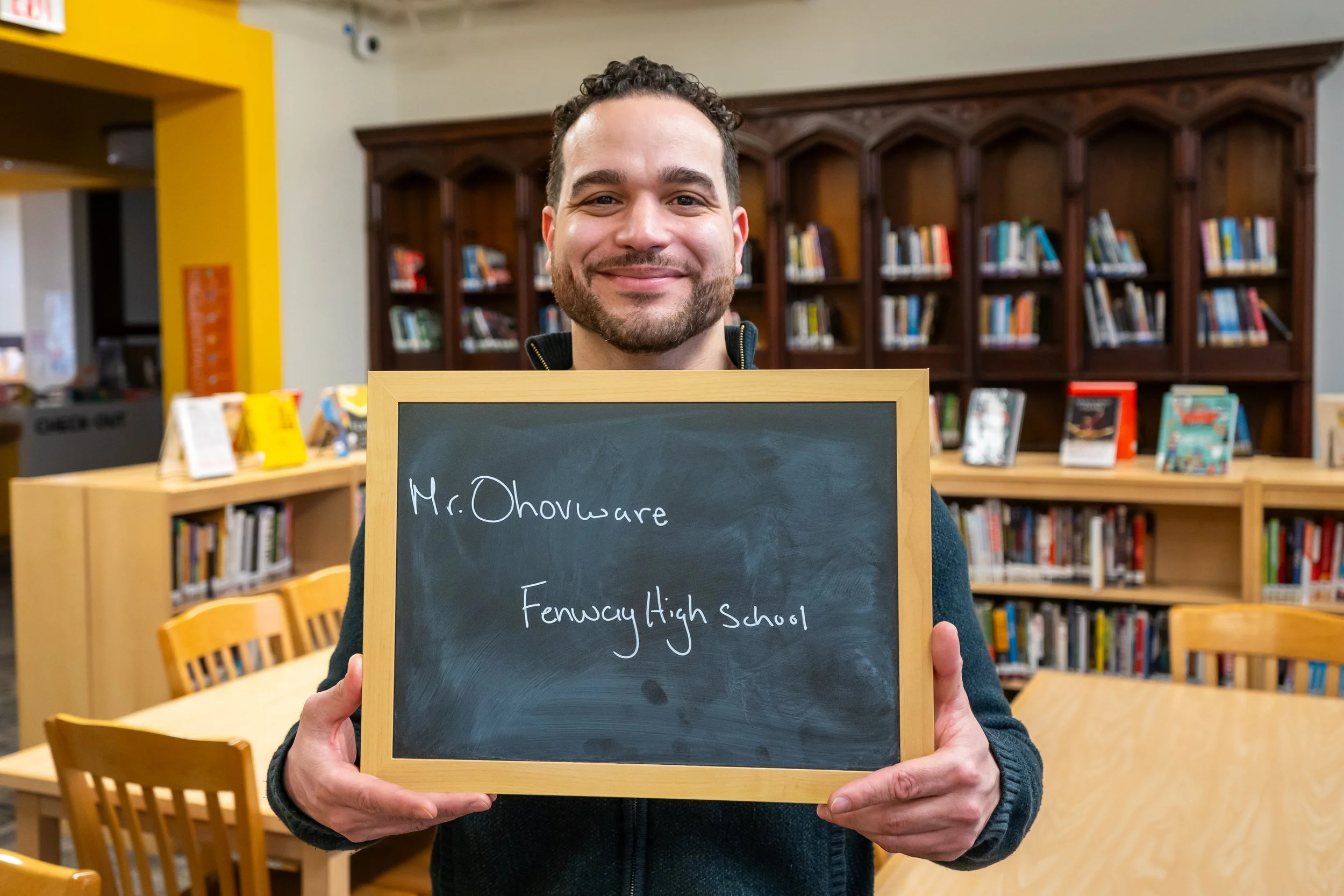 Boston educator poses with a chalkboard.