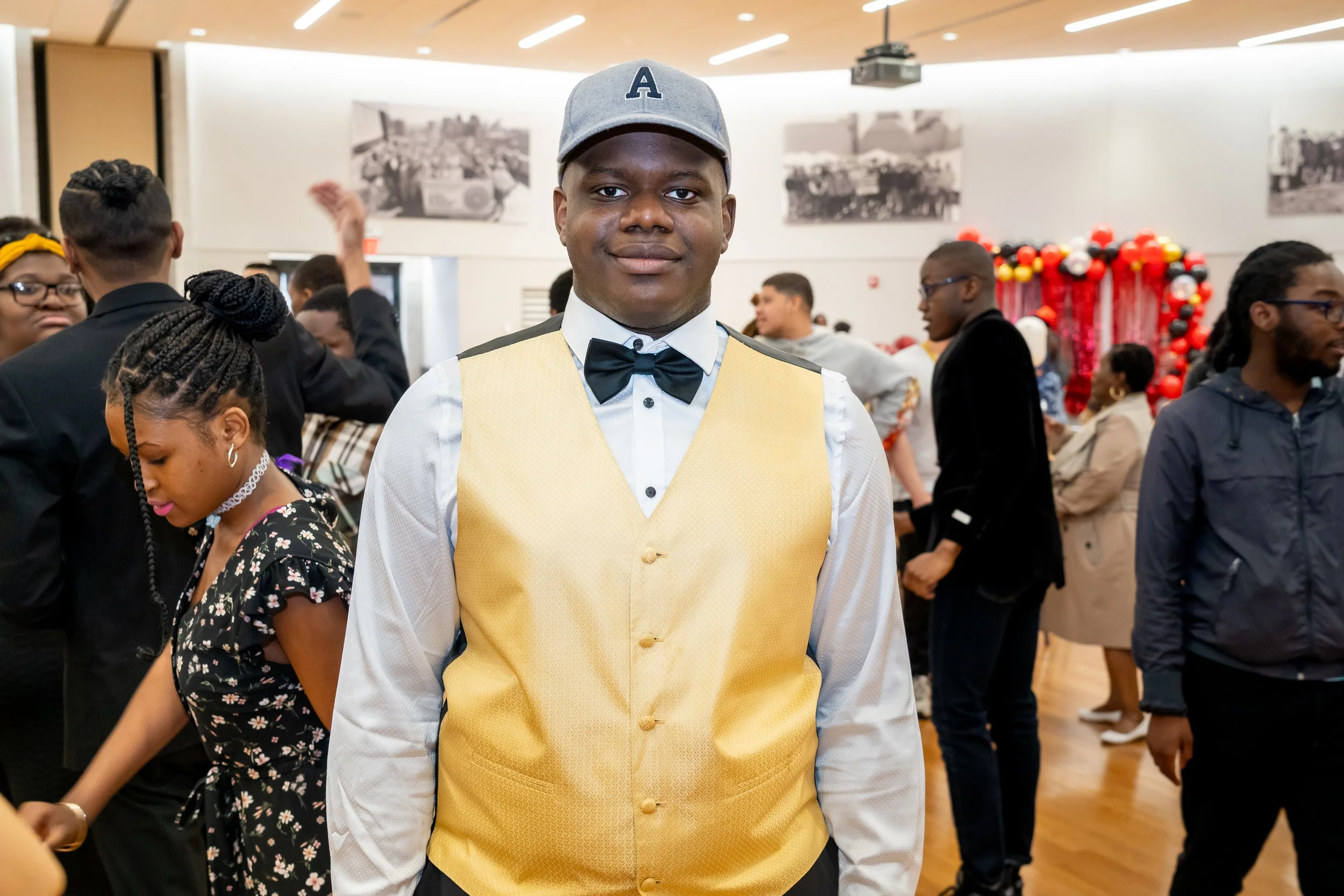 Boston Public Schools student in a gold vest and white tuxedo shirt poses for a photo. 