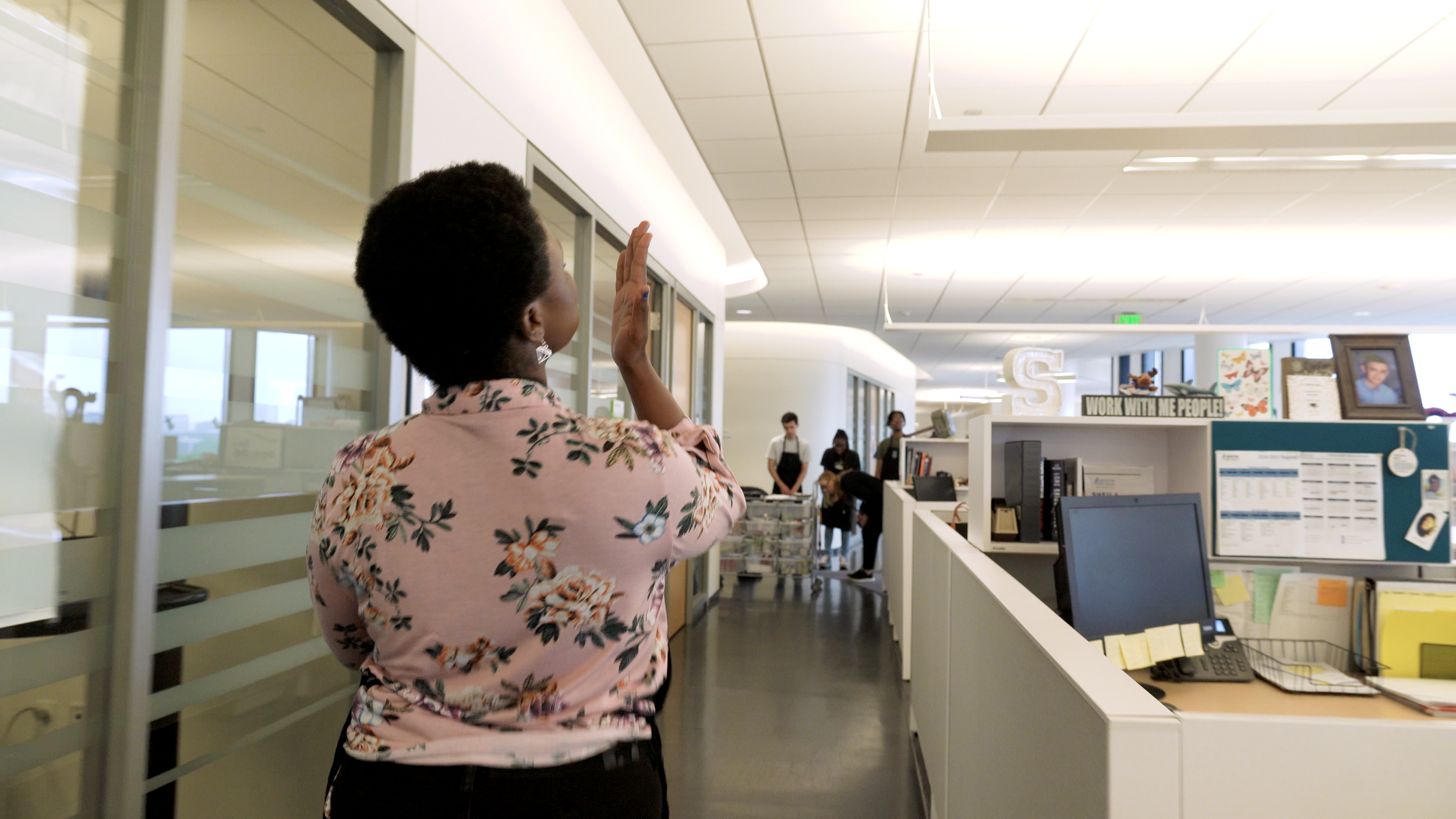 Former Boston Public Schools student Ophelia Hughes walks down a hallway blowing kisses. 