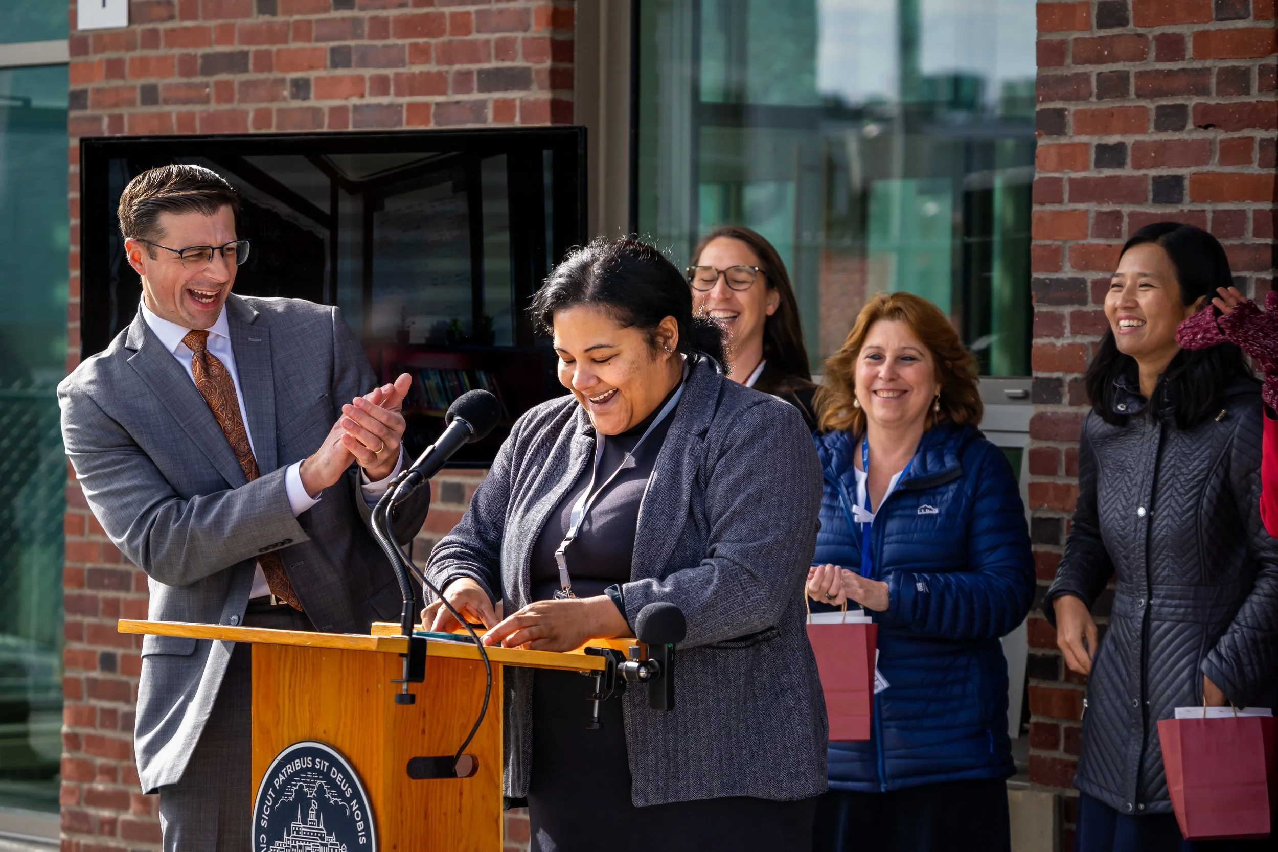 A City of Boston translator smiles while standing at a podium.