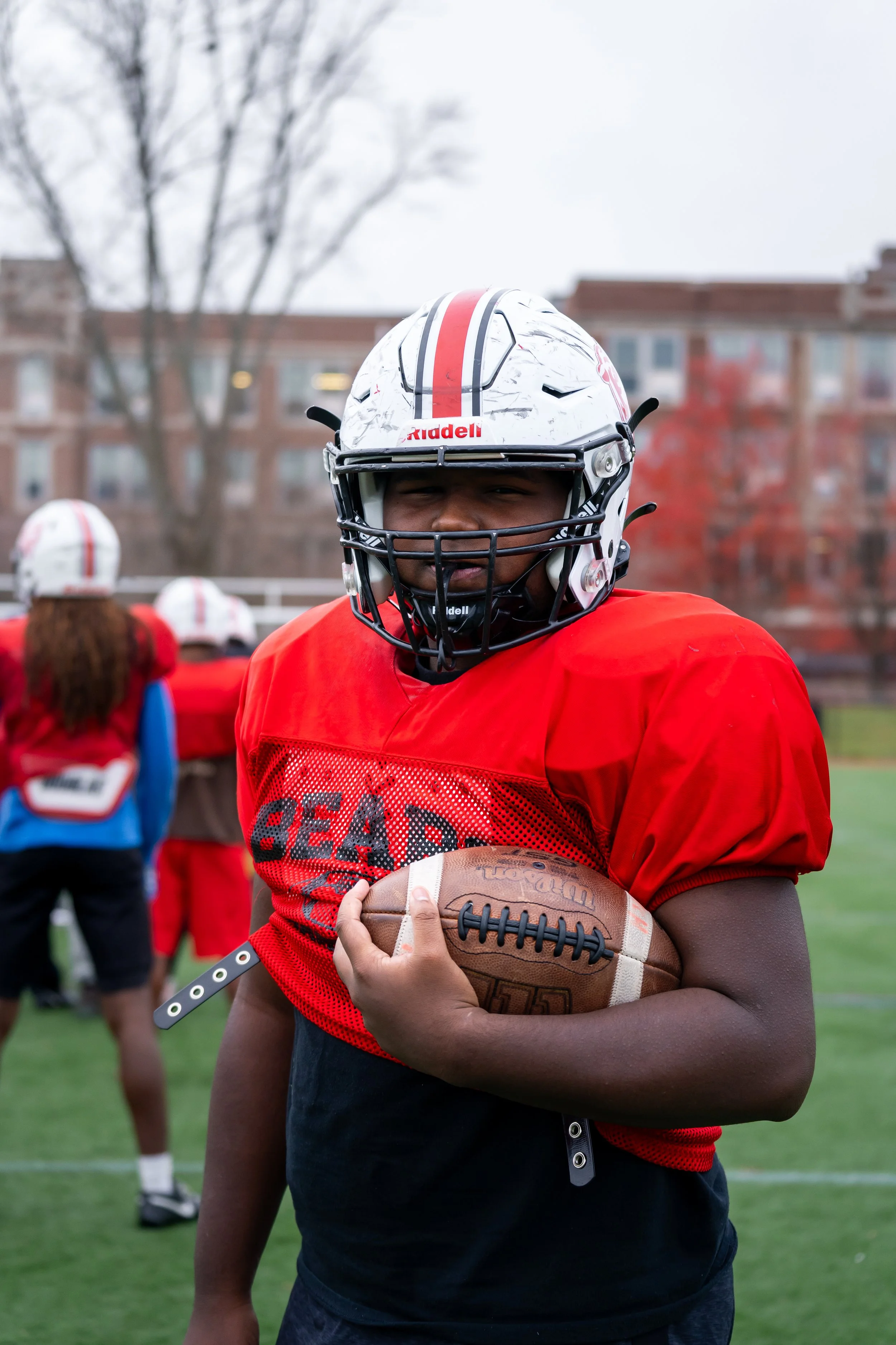 Boston Public Schools football player Edgar Santana Castro poses with a football in his arm.
