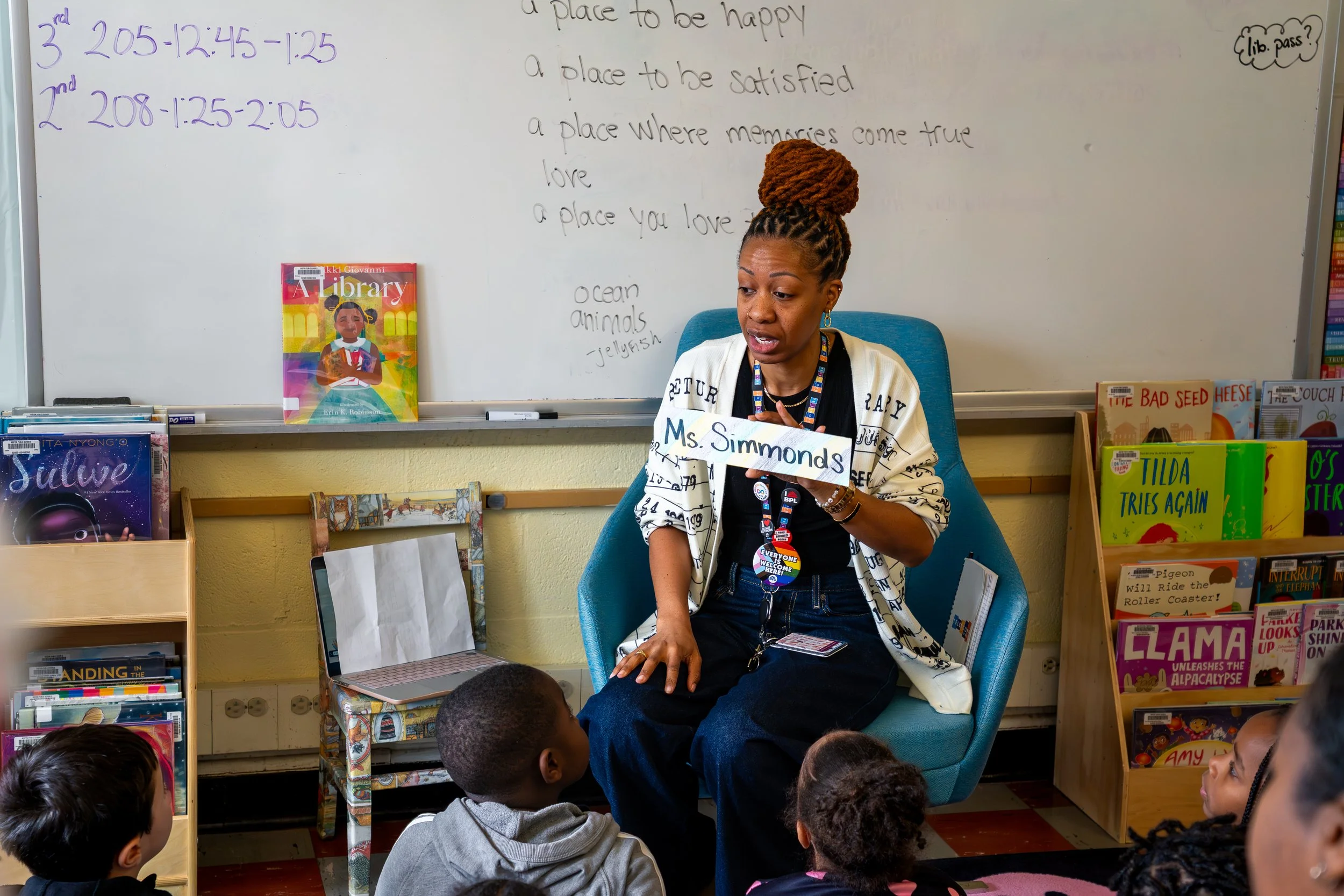 Boston Public Schools librarian Kadian Simmonds holds a colorful handwritten name tag with "Ms. Simmonds" on it.