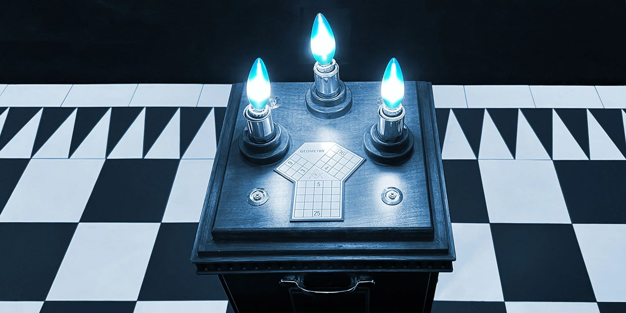 Vintage wooden box with three blue-tipped candles and a checkered puzzle game on top, placed on a black and white checkered floor.