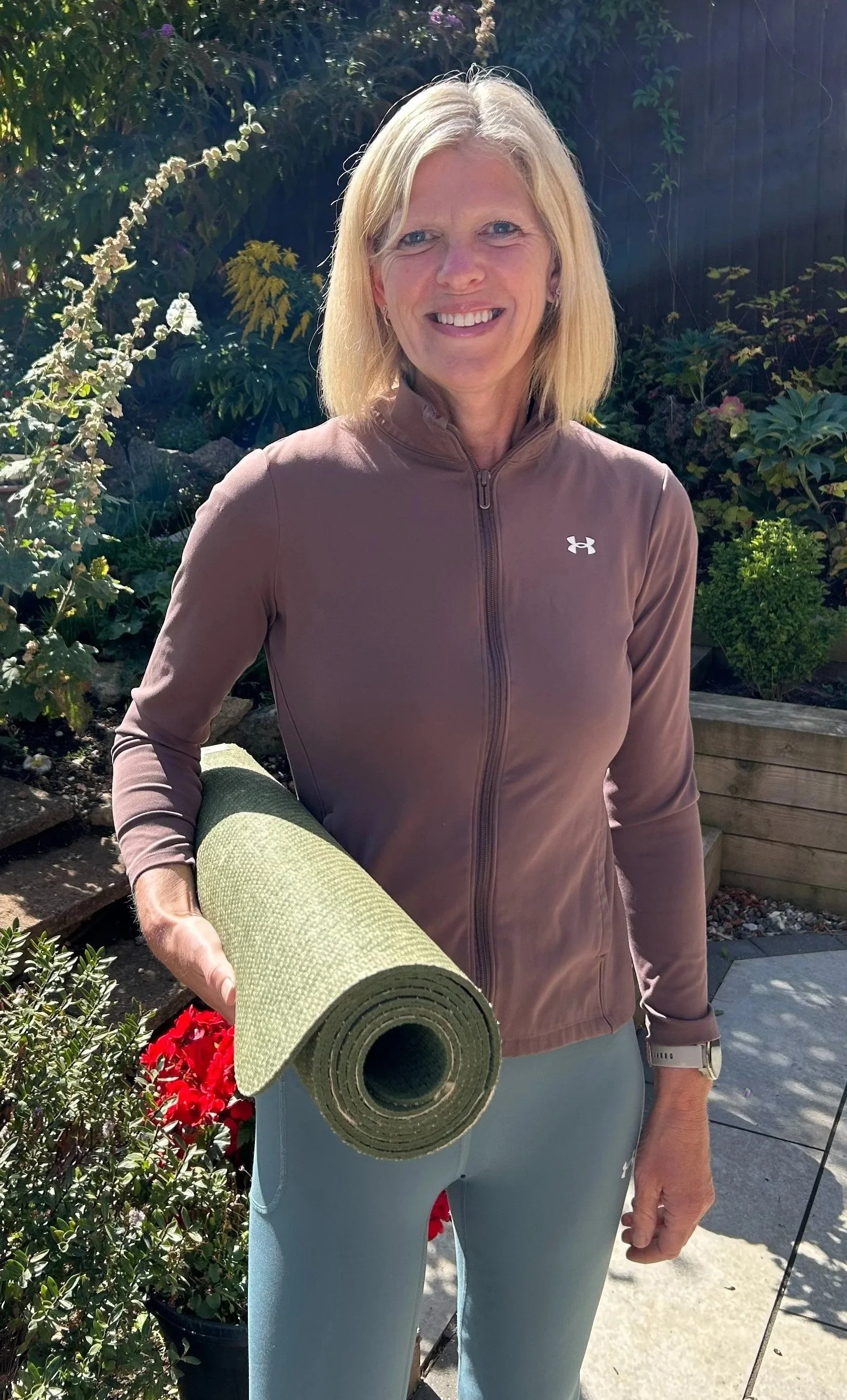 Karin Rudd holding a yoga mat outdoors.