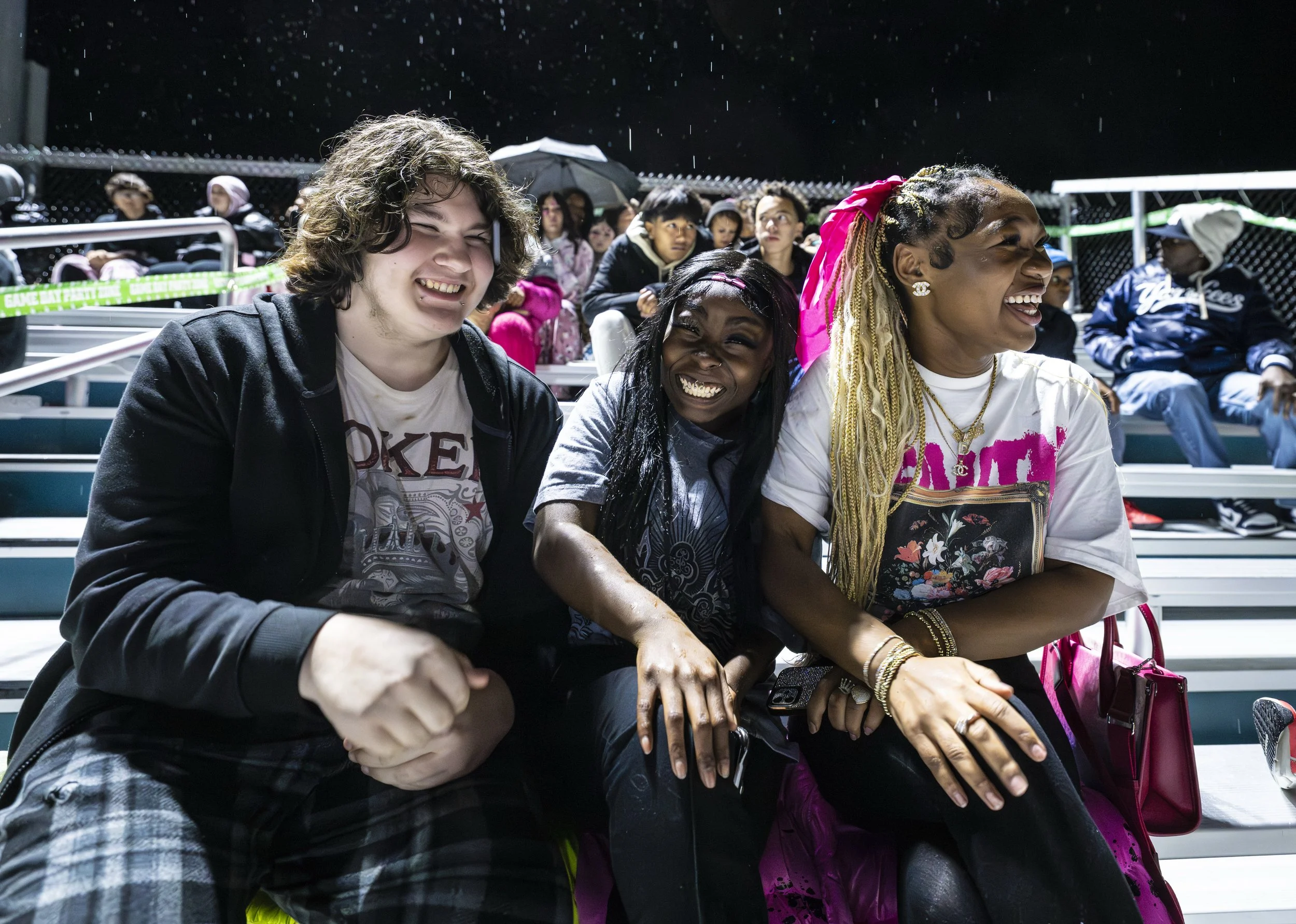 From left, Cole, Divay and Nayella watch the Greece Olympia Griffins face the Rush-Henrietta Comets during a football game Oct. 17, 2025, at Greece Olympia High School. The students sit in the Greece Olympia student “Party Zone” as Rush-Henrietta lea