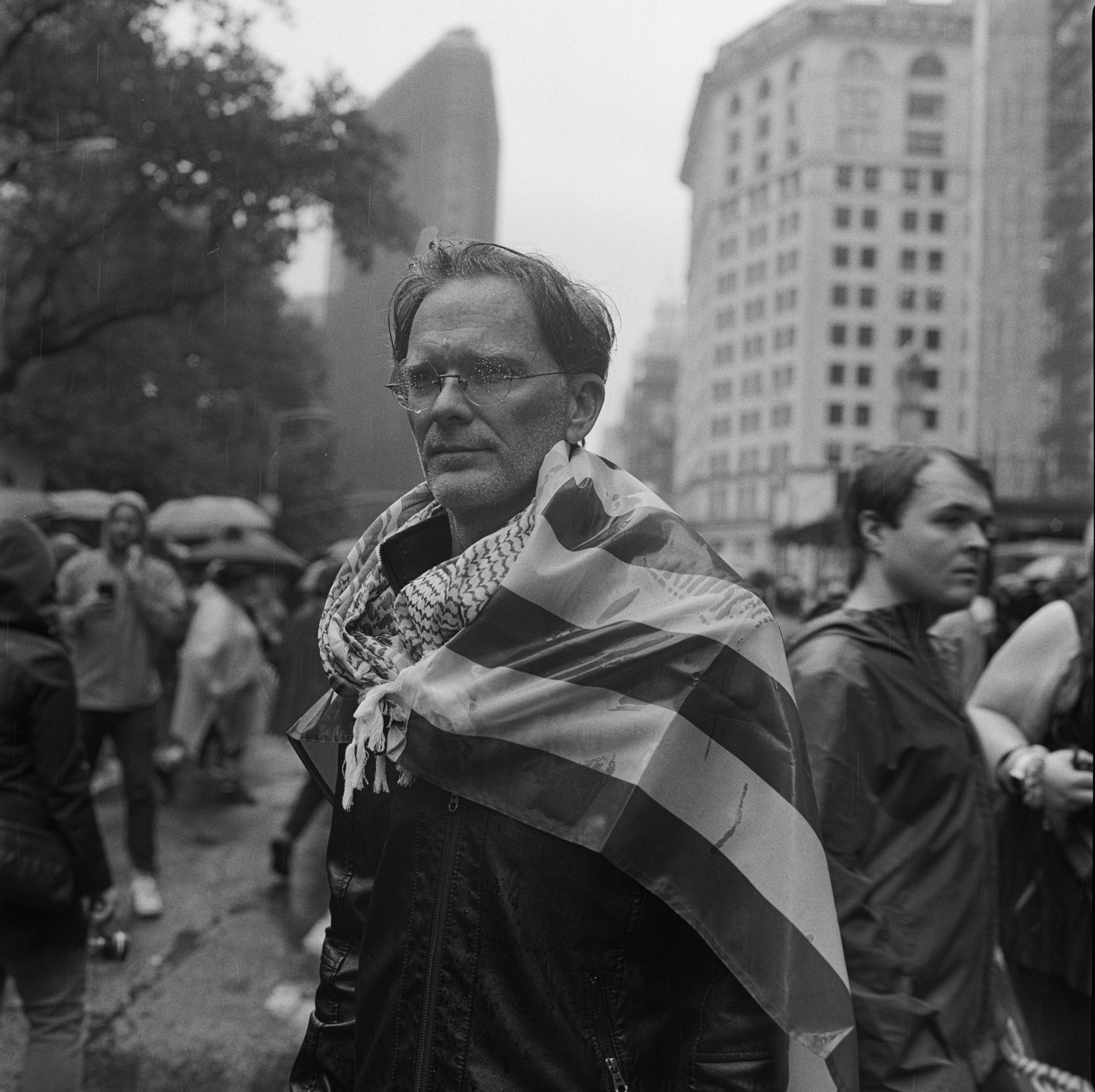 An anonymous demonstrator draped in an American flag stands at the end of the No Kings demonstration June 14, 2025, on Fifth Avenue in New York City. The photograph was shot on Ilford HP5 Plus film.
