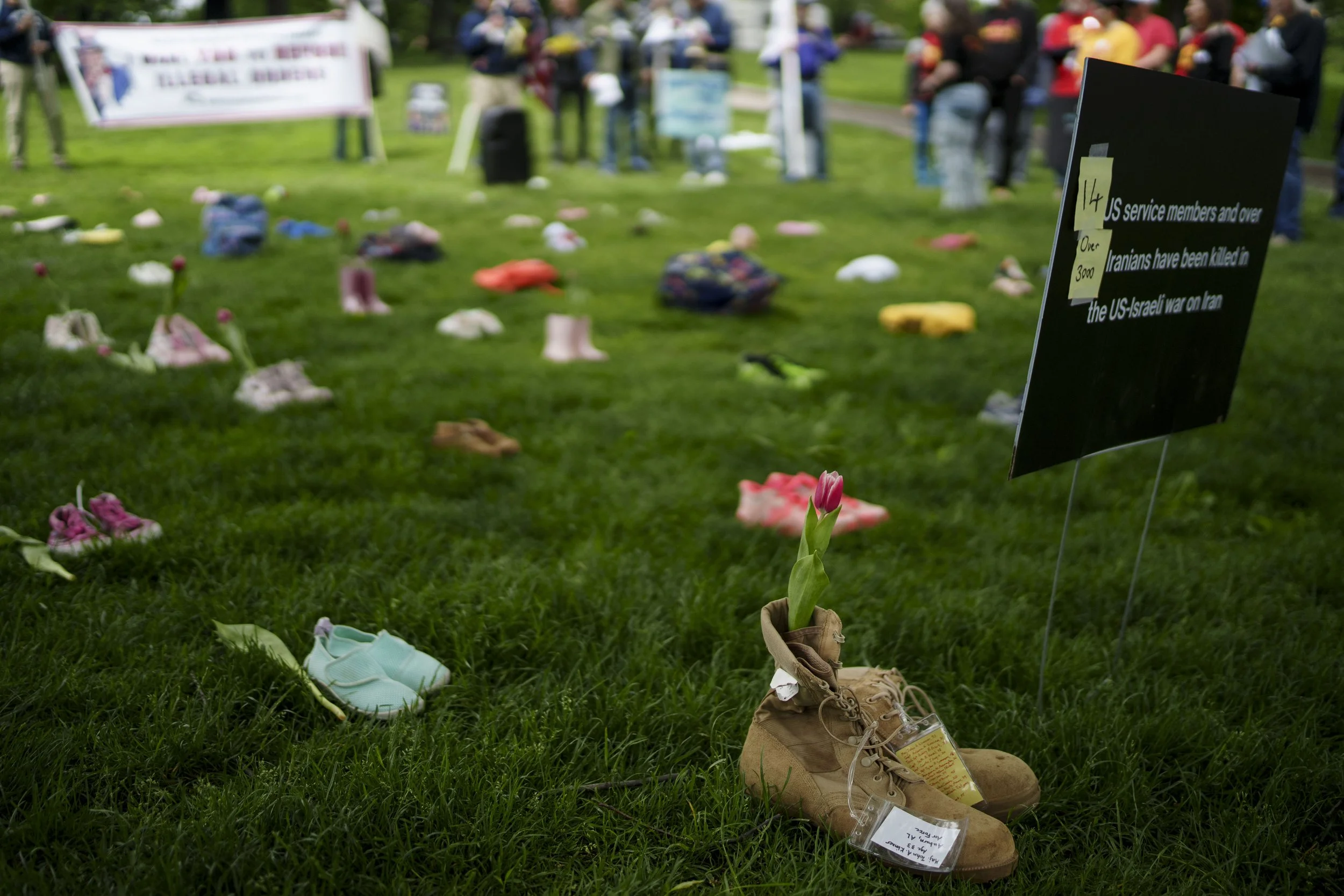a military boot has flowers placed in it representing service members and children killed by Israeli and American missiles in Gaza at a Veterans for Peace event in the Boston Common, May 25, 2026
