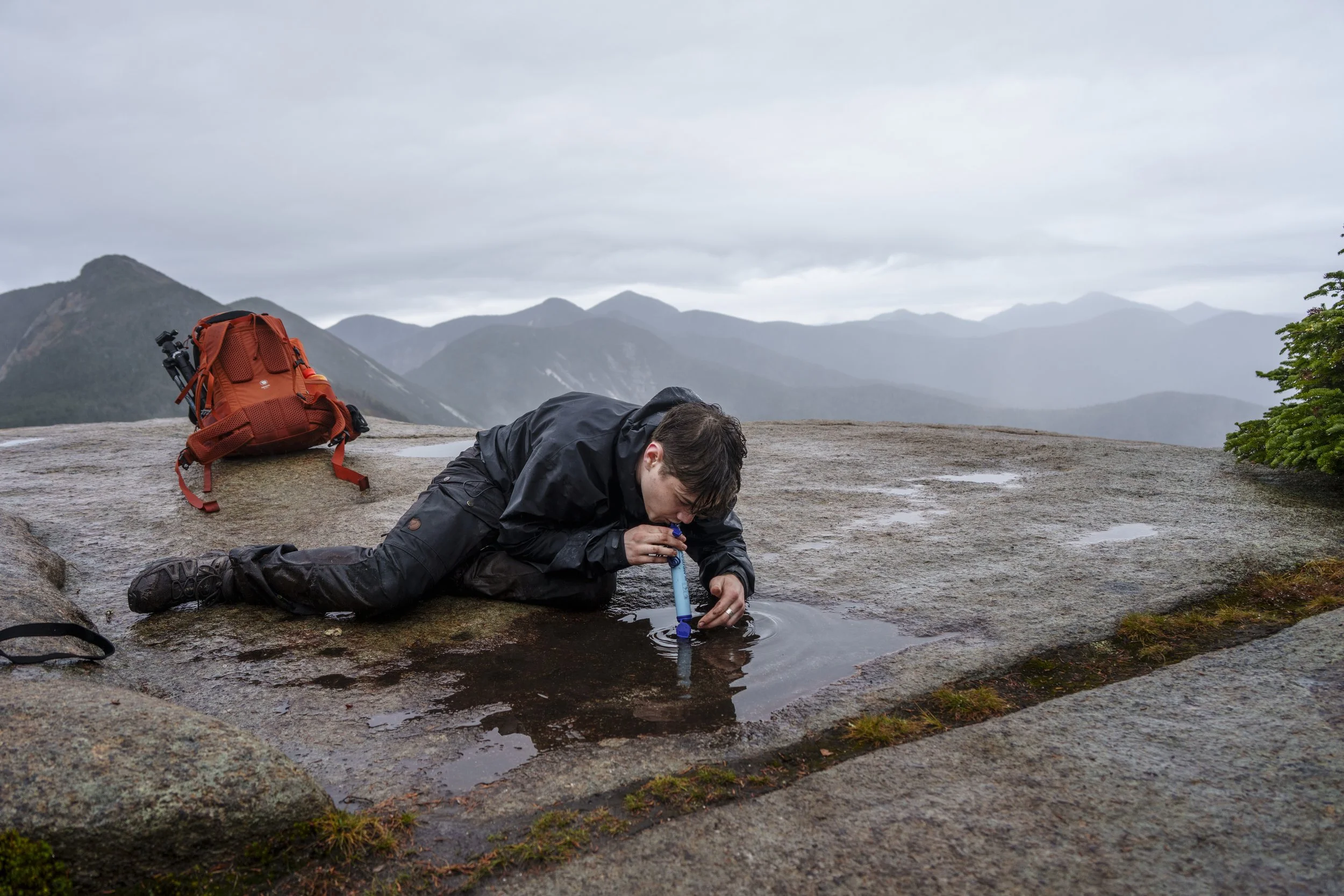 Carlos Sanchez uses a LifeStraw to drink from a puddle atop Armstrong Mountain in the Adirondack Mountains on Oct. 13, 2025. Sanchez was part of a group of students on a multi-day expedition that ran out of potable water after underestimating the dis