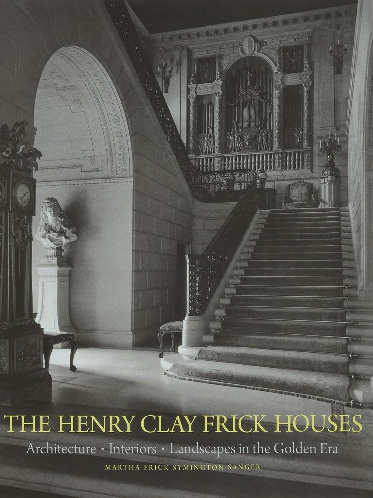 Cover of a book titled "The Henry Clay Frick Houses" showing an elegant staircase inside a historic building with ornate details, sculptures, a bust on a pedestal, and decorative wall and ceiling features.