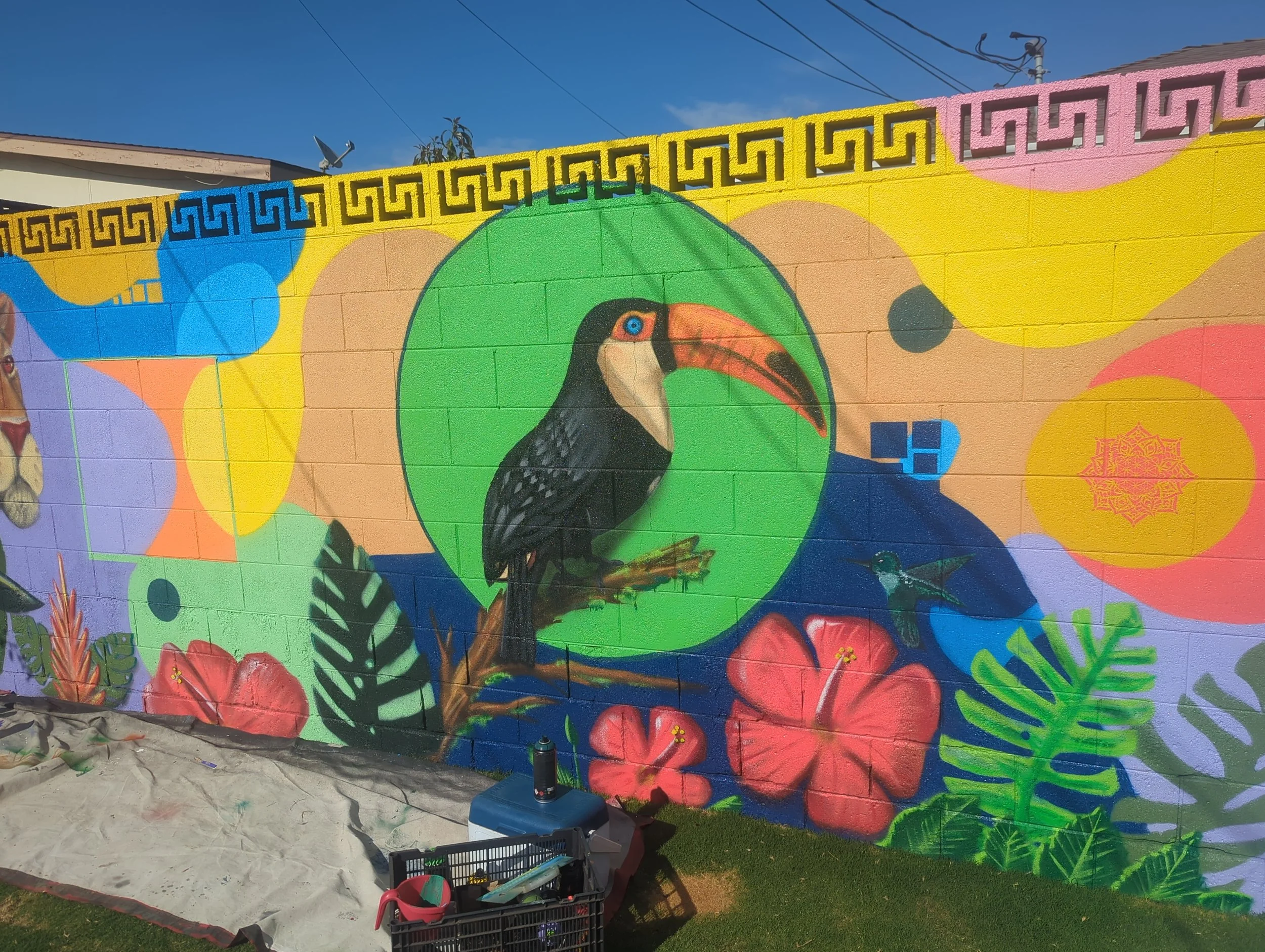 Colorful mural of a toucan bird painted on a brick wall with vibrant abstract shapes and patterns.
