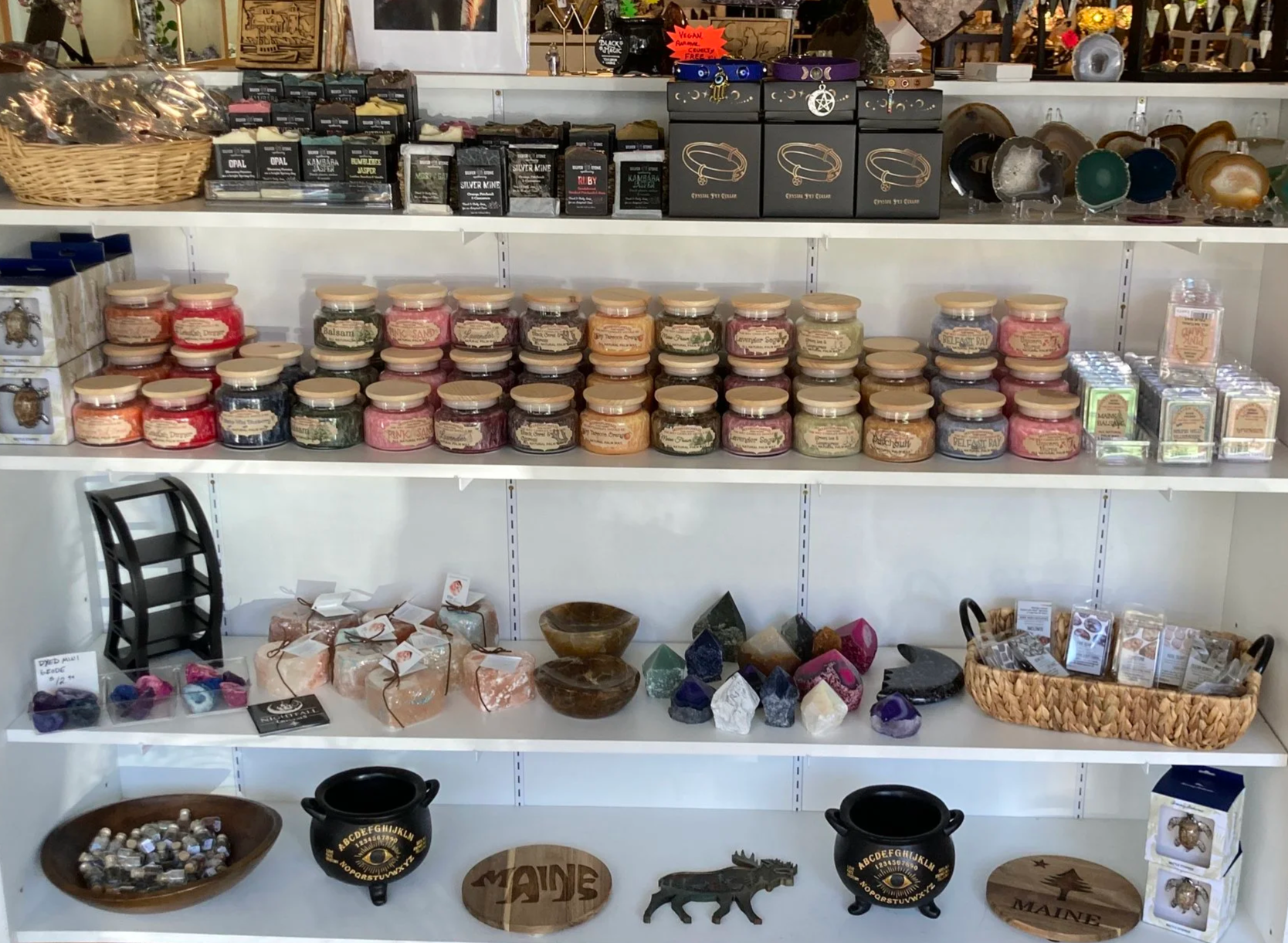 Shelves displaying various crystals, gemstones, candles, jewelry, and decorative items in a store.