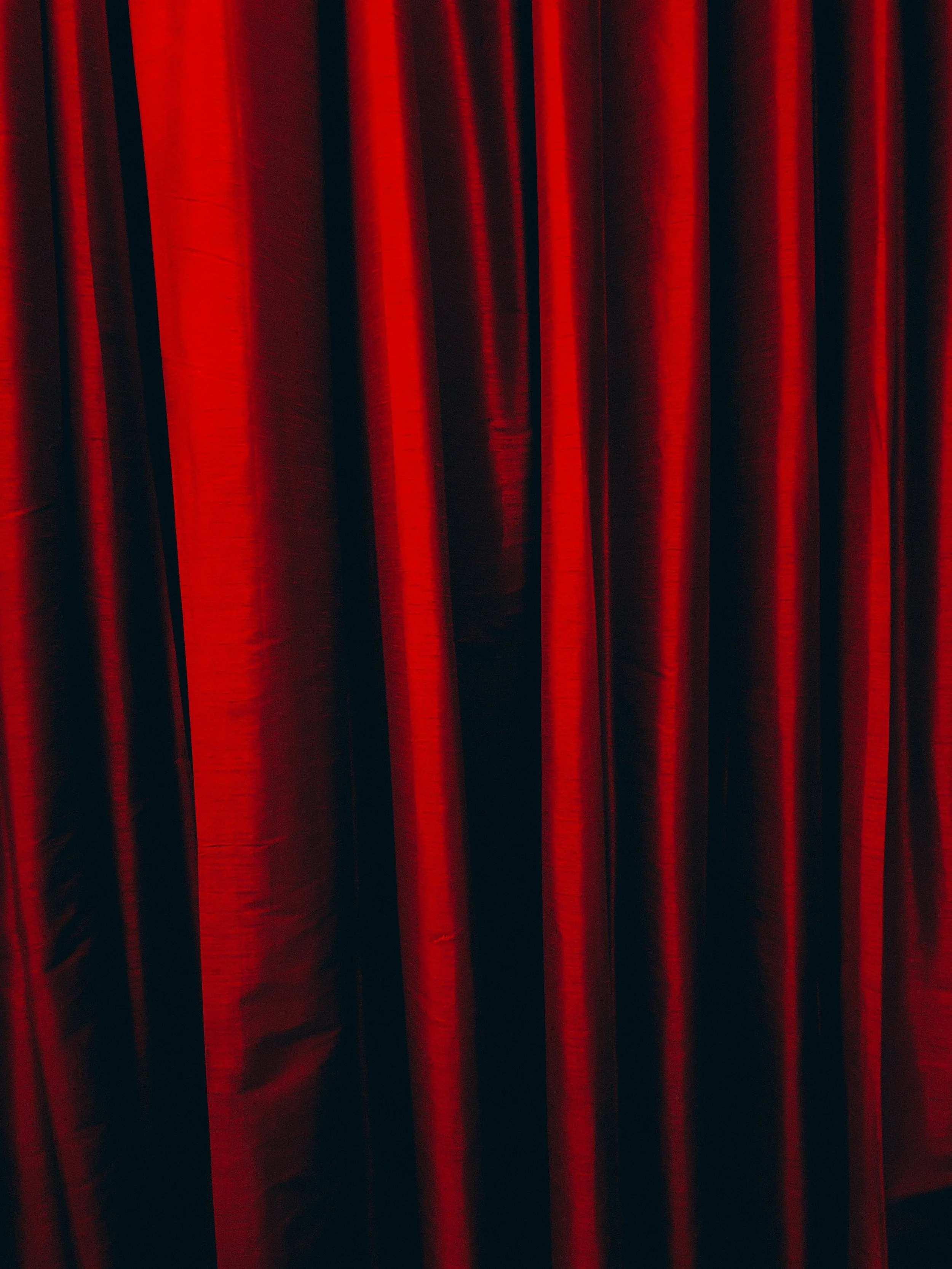 Red stage curtain with black shadows in between.