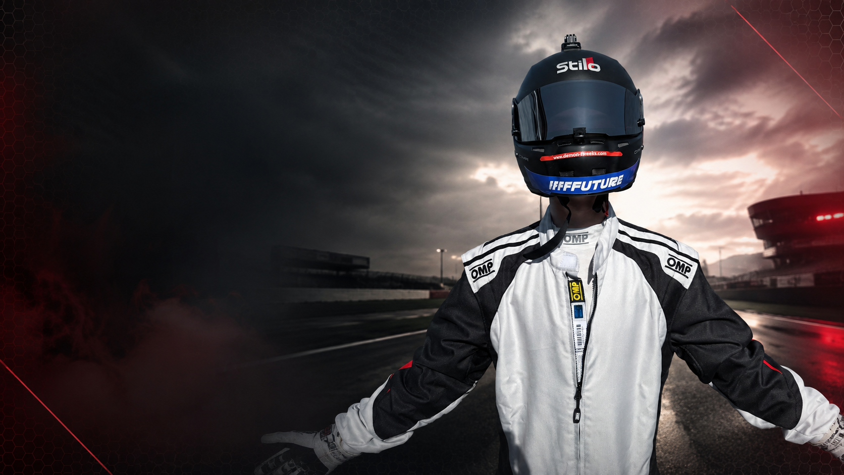 Race car driver in a racing suit with arms outstretched, standing on a race track during dusk, wearing a blue racing helmet with dark visor.
