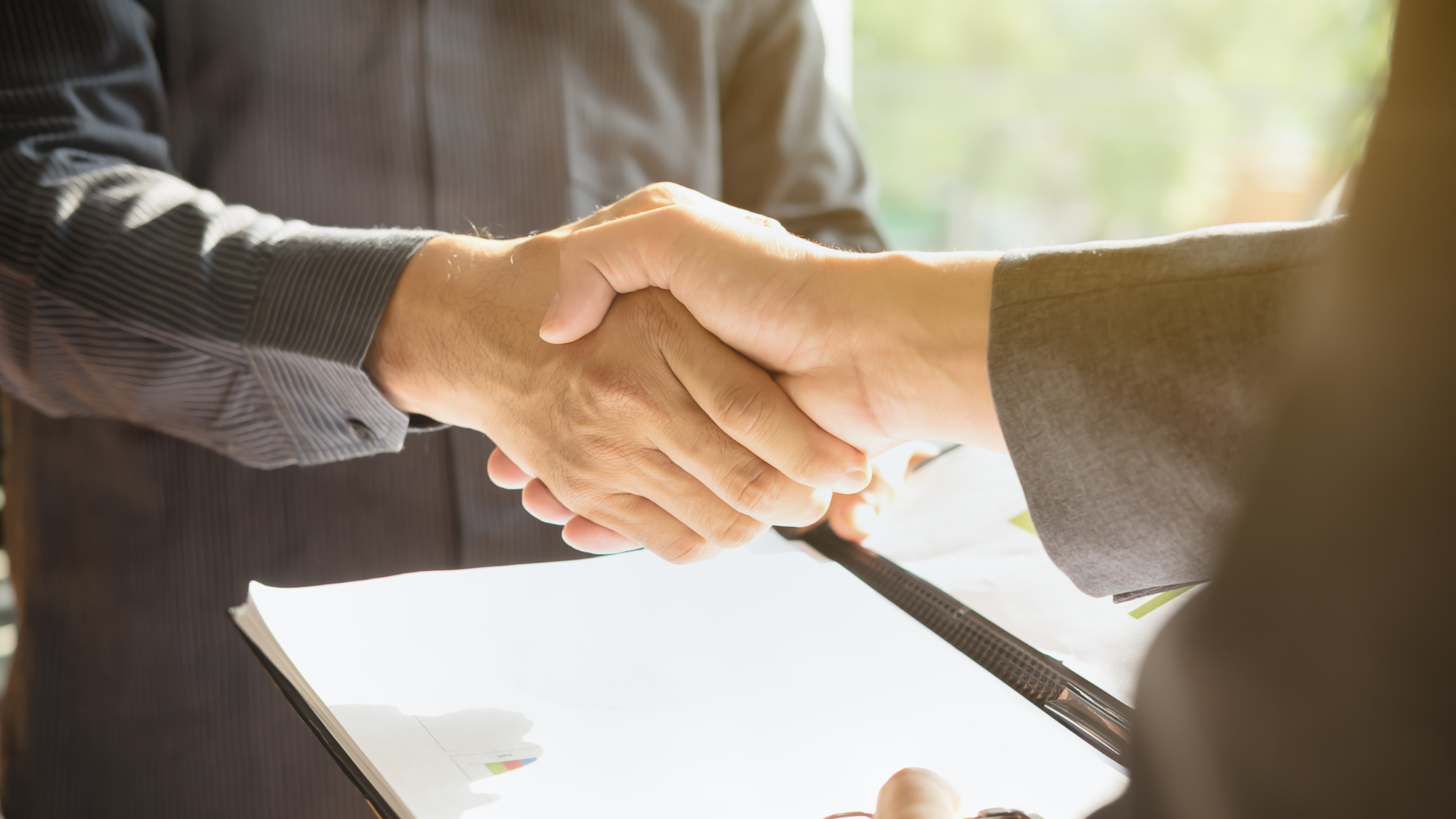 Two people shaking hands during a business meeting or agreement.