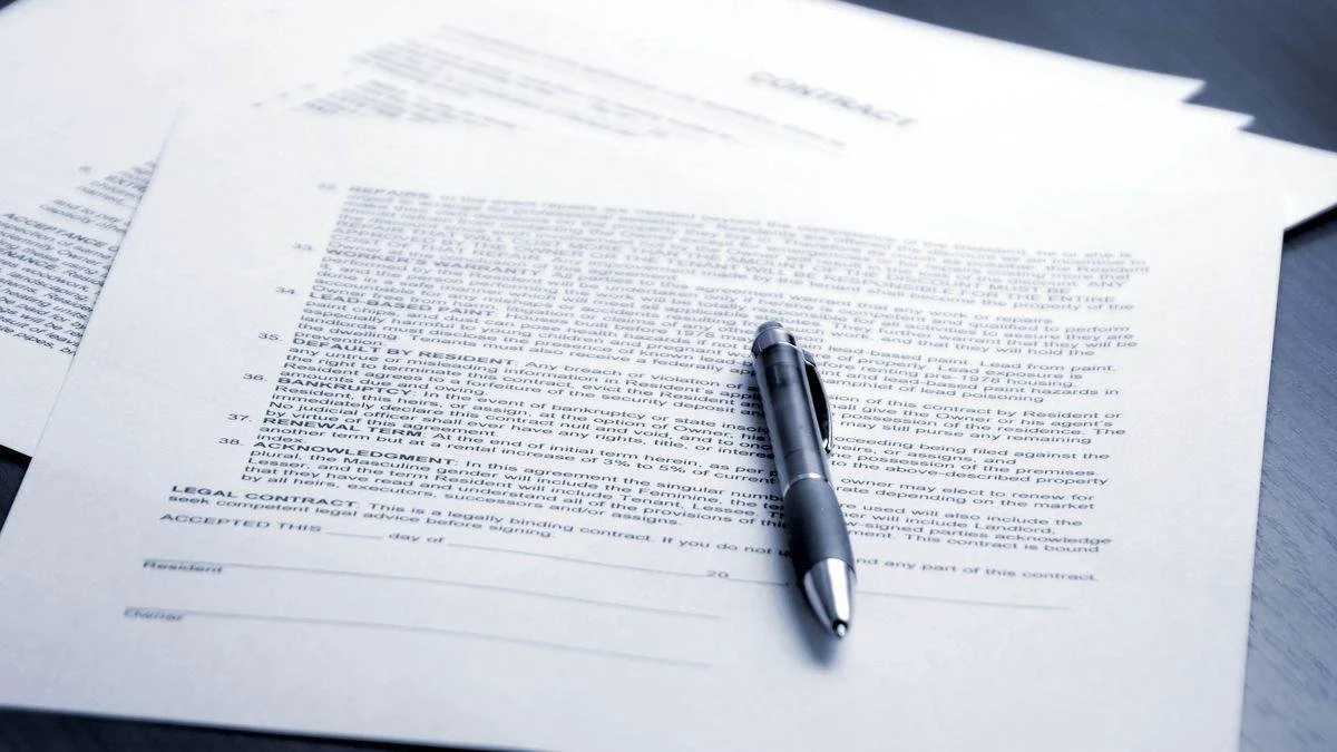 Des papiers juridiques ou contractuels avec un stylo noir posé dessus.