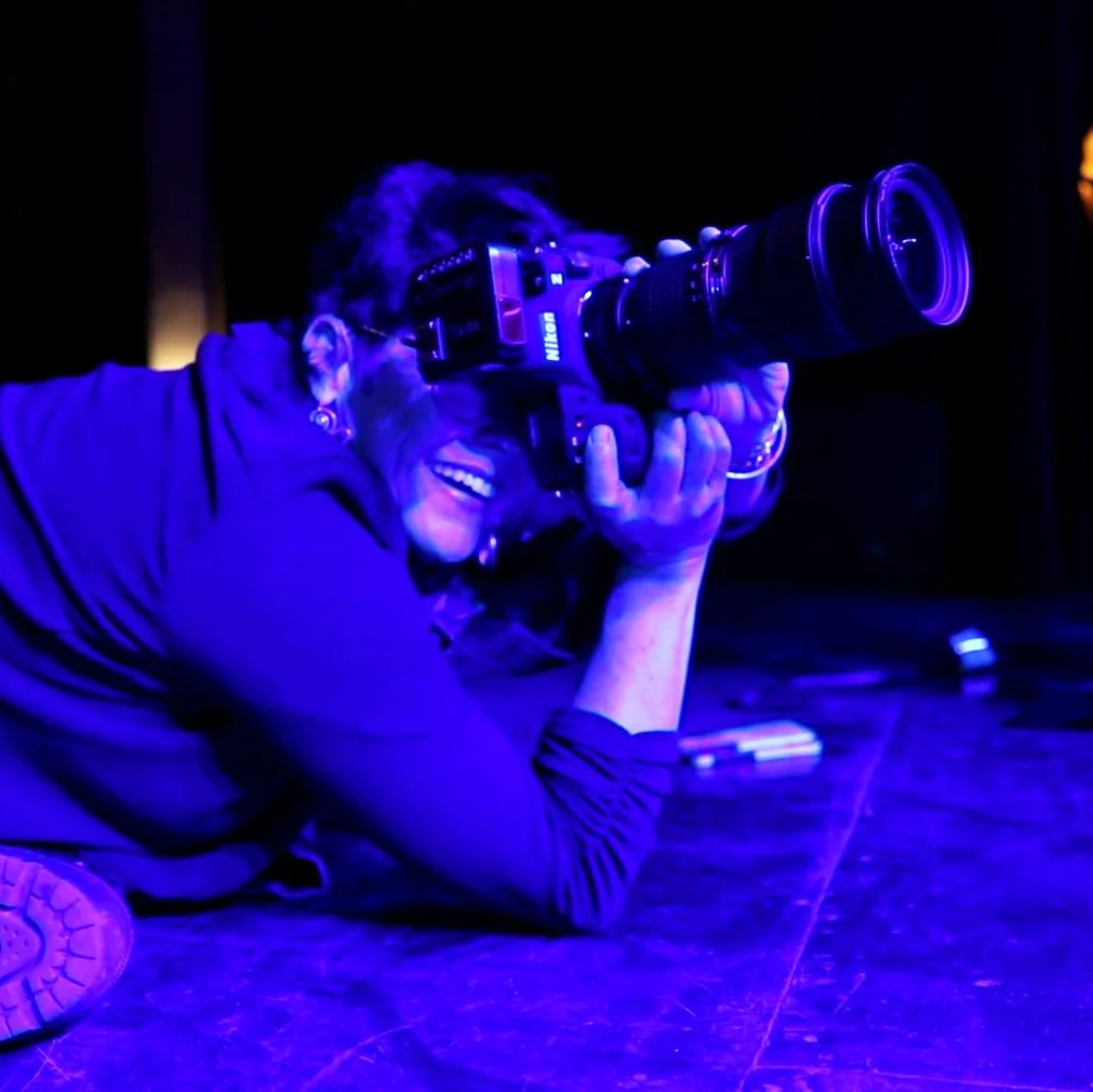 photographer amy ijams lays on the floor of a stage set with blue lights during a tucson event