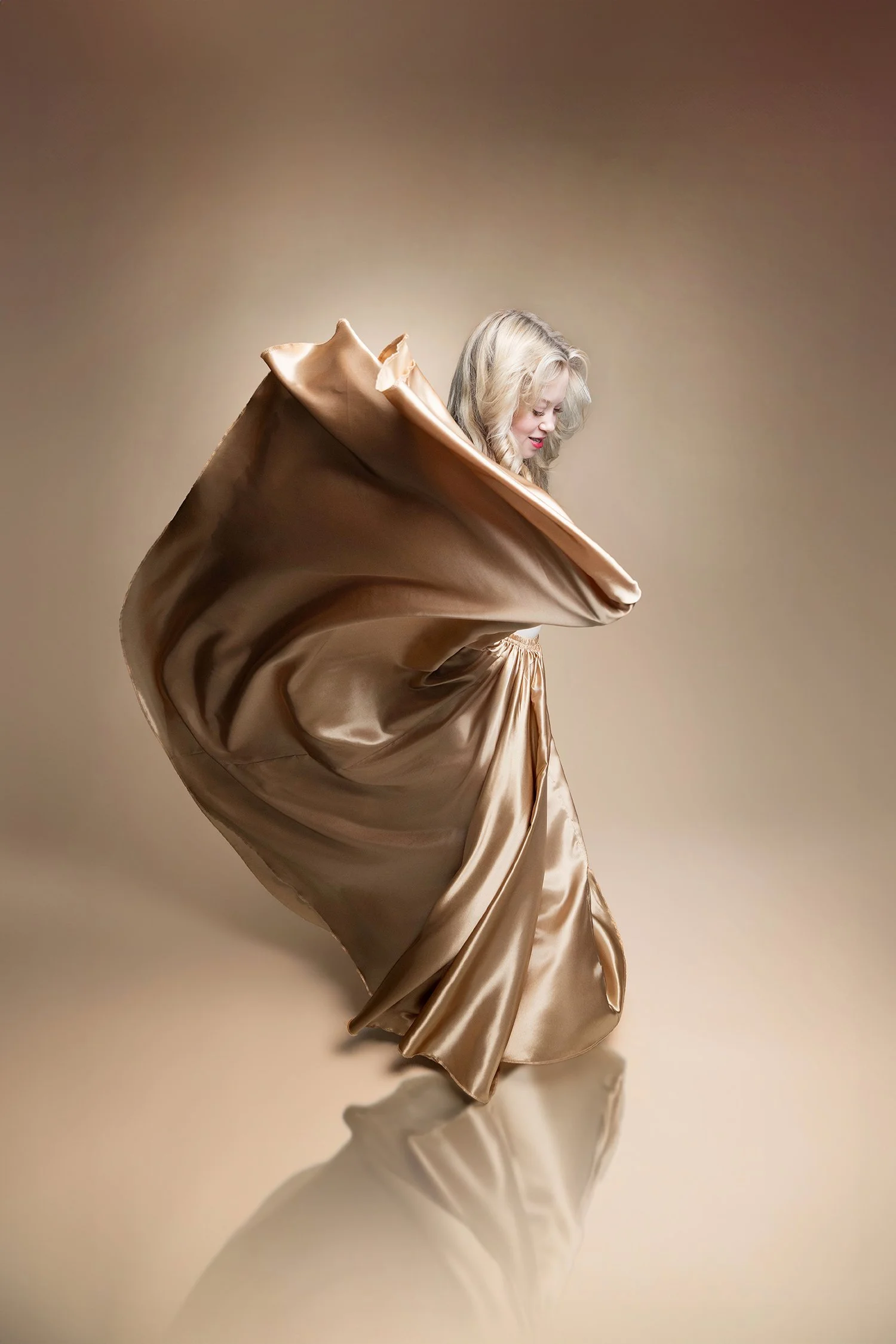 a tucson high school senior swirls a large gold skirt during a photo shoot at amy ijams photography studio