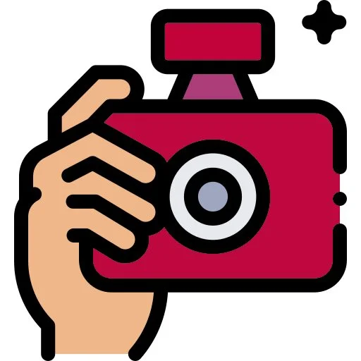 A hand holding a red camera with a flash and a lens, and a small black plus sign in the top right corner.