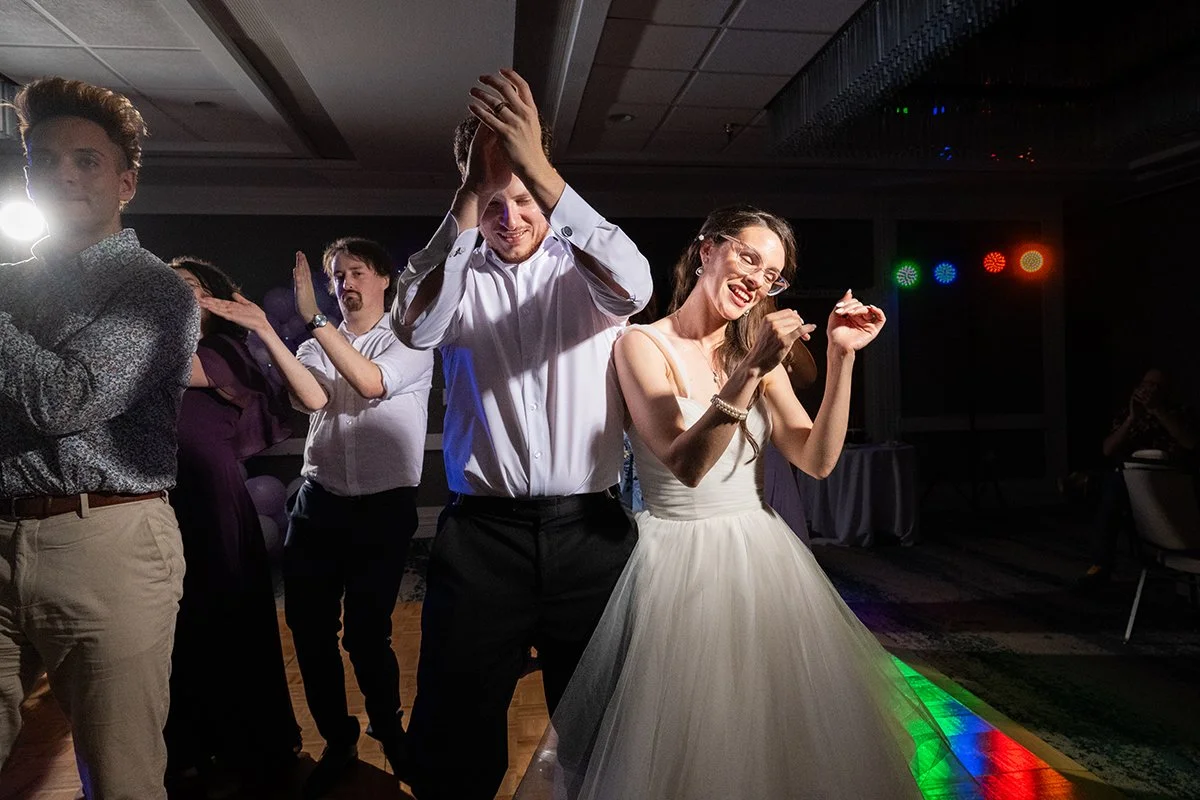 People dancing at a wedding reception, including a woman in a white wedding dress and a man in a white shirt.